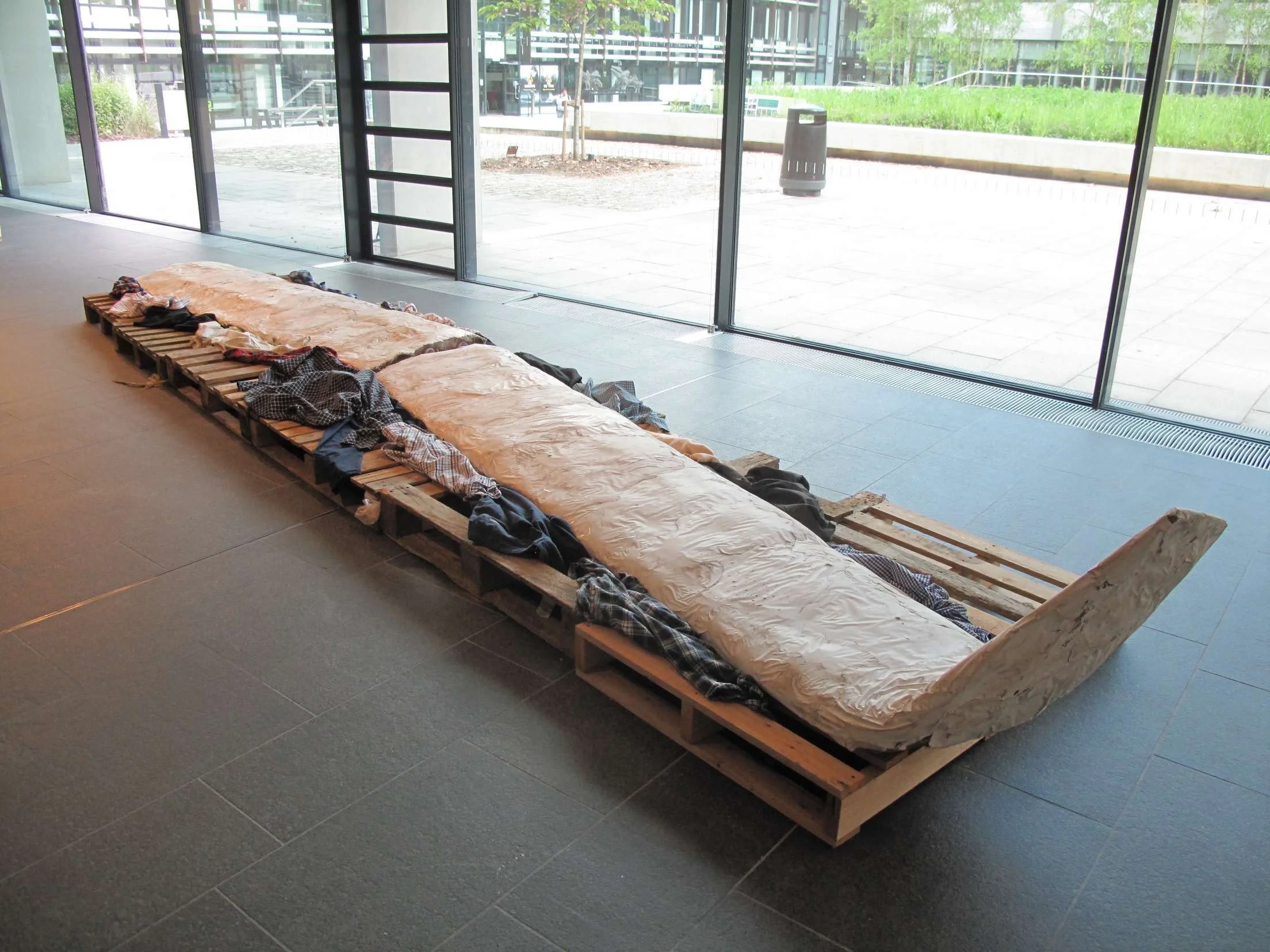 Most Men Lead Lives Of Quiet Desperation iii, 2023, Jesmonite, chicken wire, PVC pipes, scrim, clothing, wooden pallets.