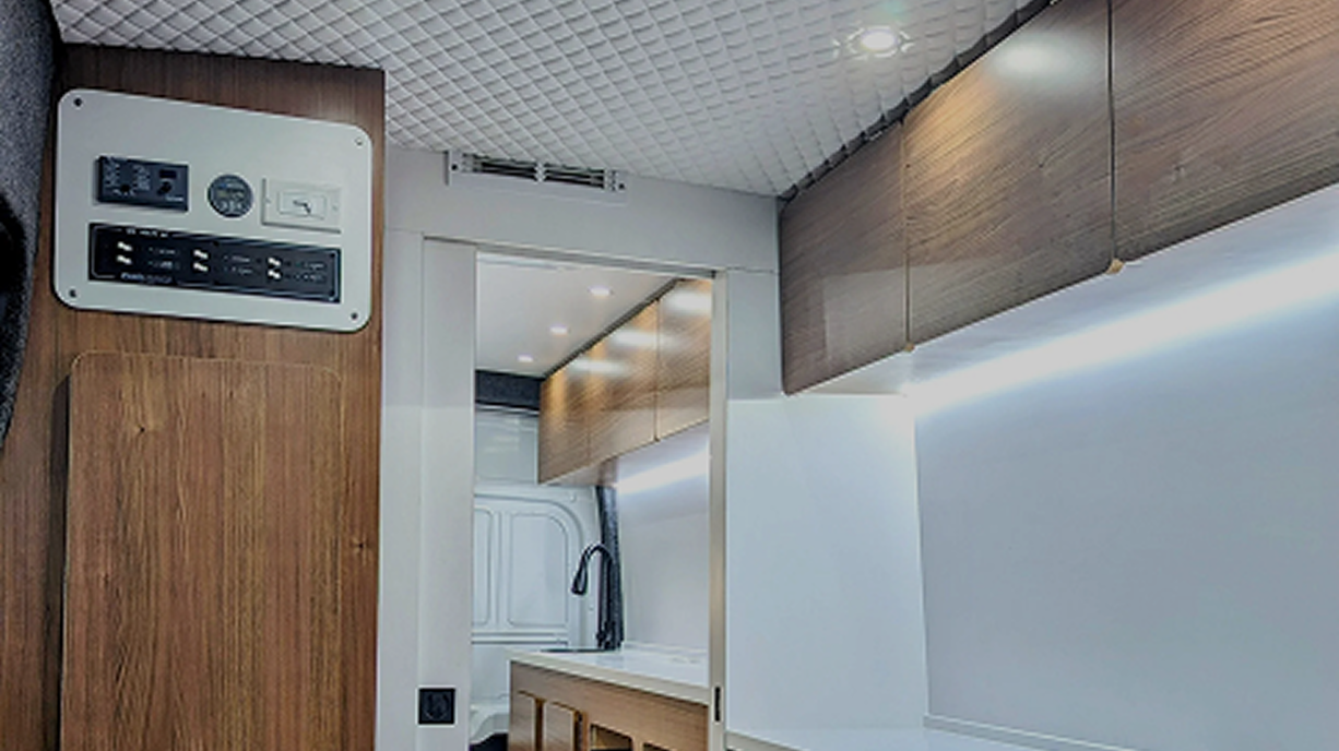 Interior of a modern kitchen with wooden cabinets, a sink with a black faucet, and a white wall with subtle lighting.