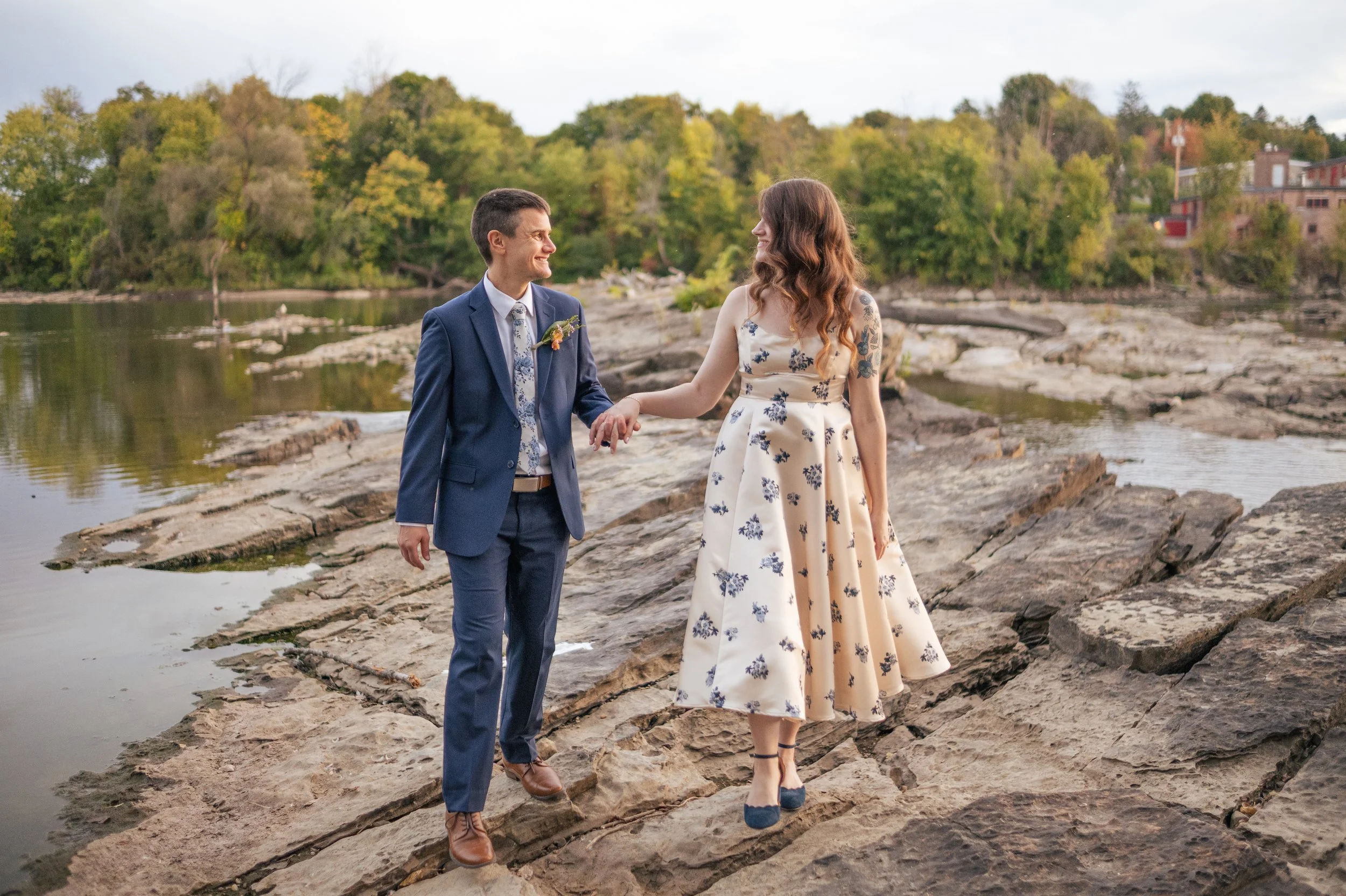 A couple walks across a river holding hands