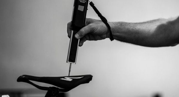 Person measuring bike saddle with tool