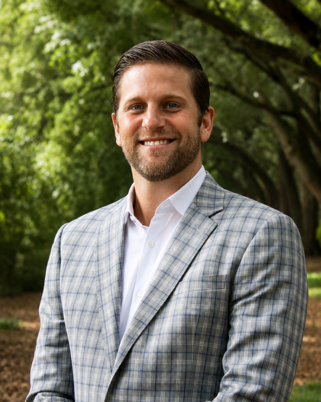 Smiling person in blue checkered suit jacket outdoors