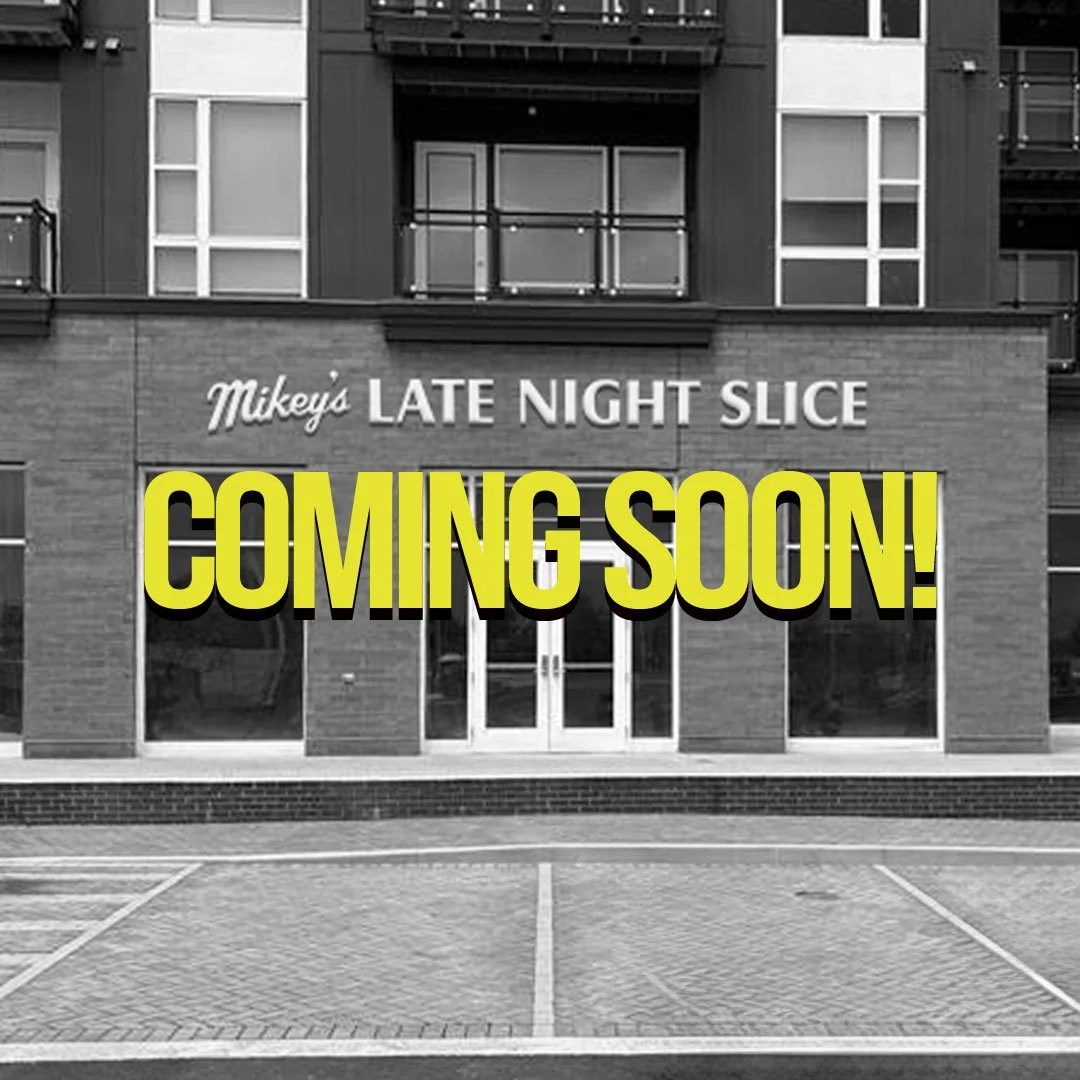 Storefront with sign 'Mikey's Late Night Slice' and large yellow text reading 'Coming Soon!'