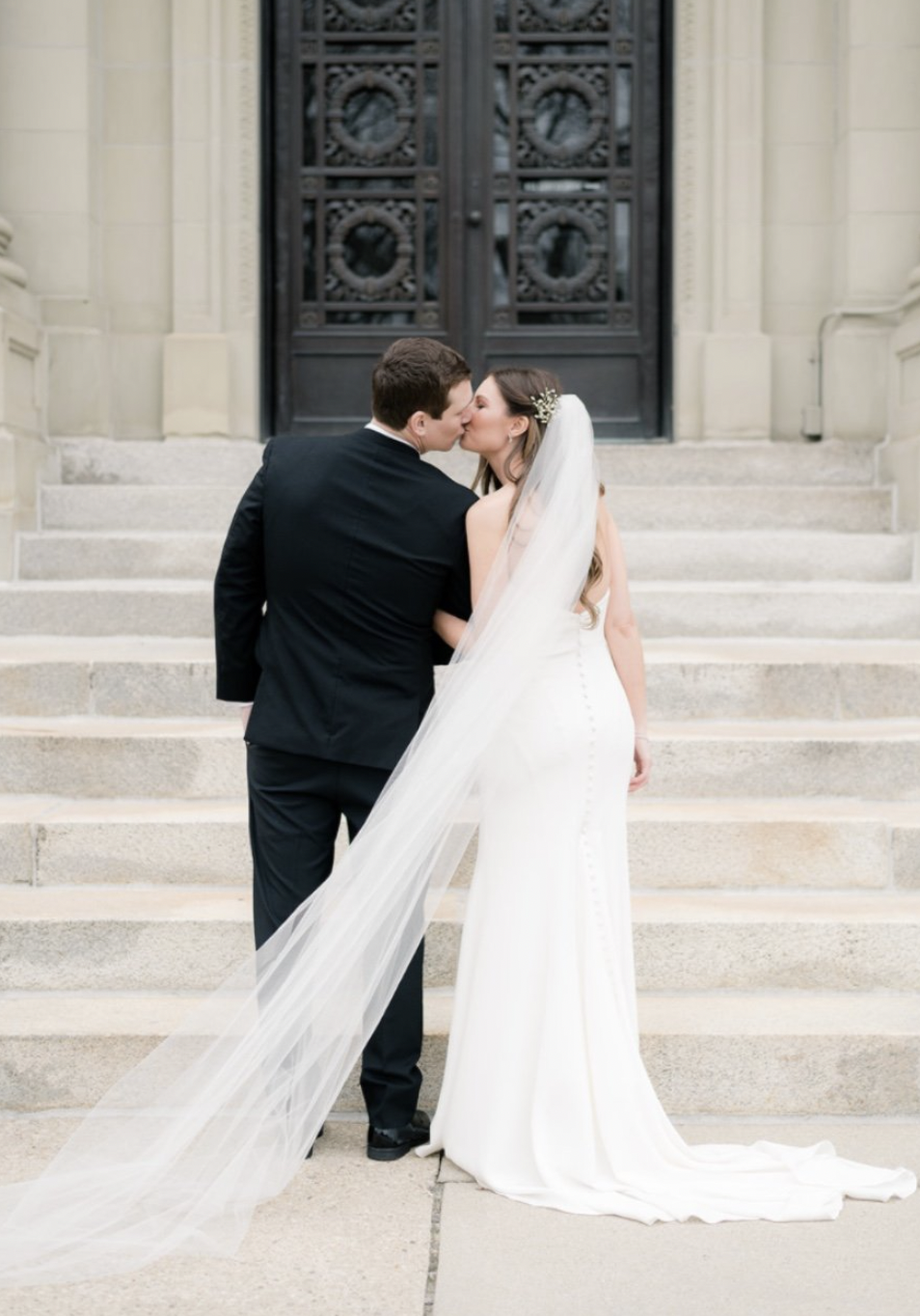 A bride and groom share a kiss on the steps outside Memorial Hall in Cincinnati