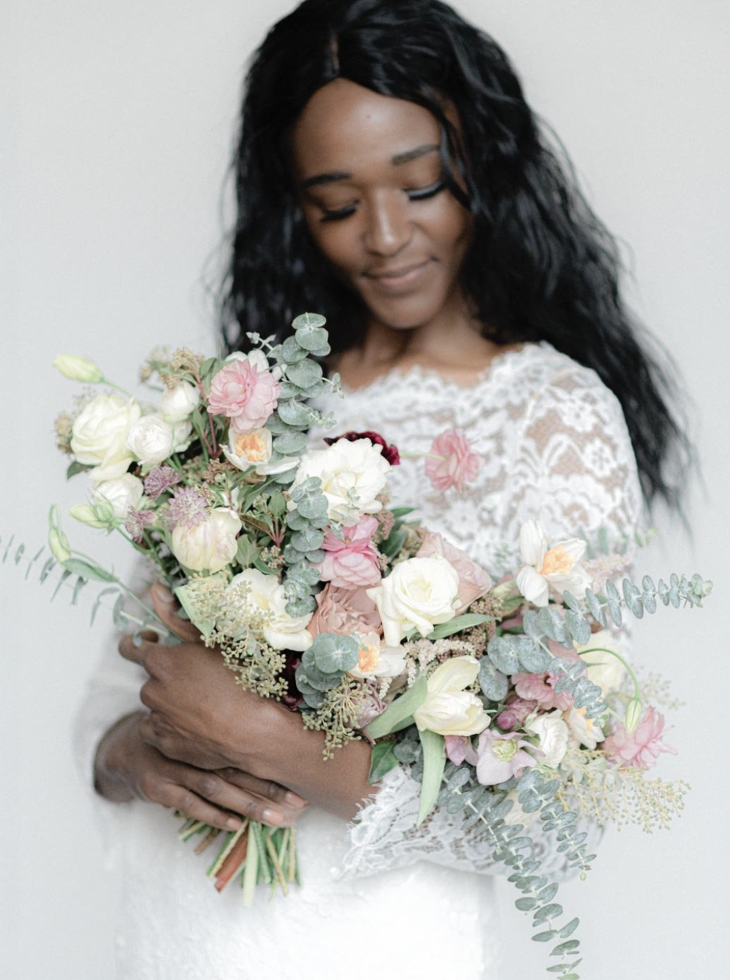 A woman with dark, wavy hair holding a large bouquet of mixed flowers in Cincinnati