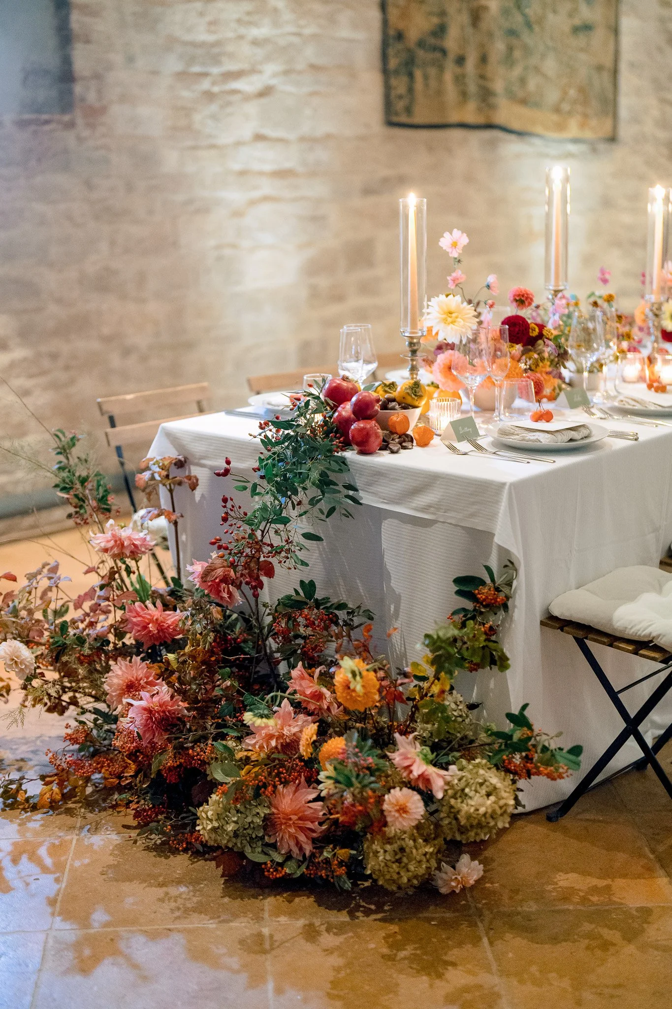 A decorated dining table with floral arrangements, candles, and plates, set for an event or celebration.