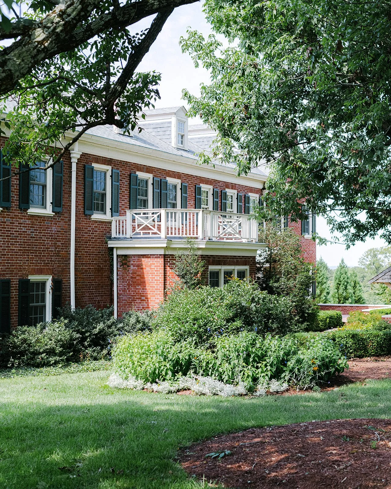 A large wedding reception tent at French House in Cincinnati. Decorated luxury floral centerpieces, surrounded by wooden chairs, with outdoor greenery visible through the open sides of the tent.
