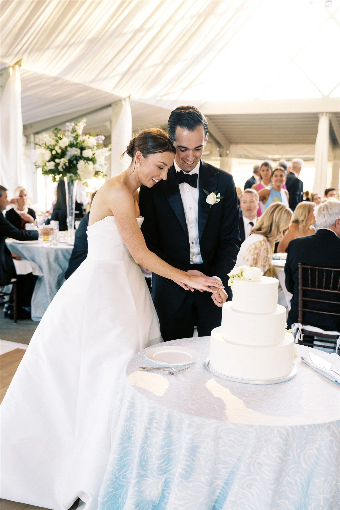 A bride and groom at a wedding cutting a tiered wedding cake together. 