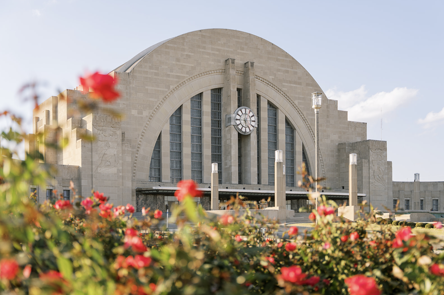 Art Deco building with clock, flowers in foreground.