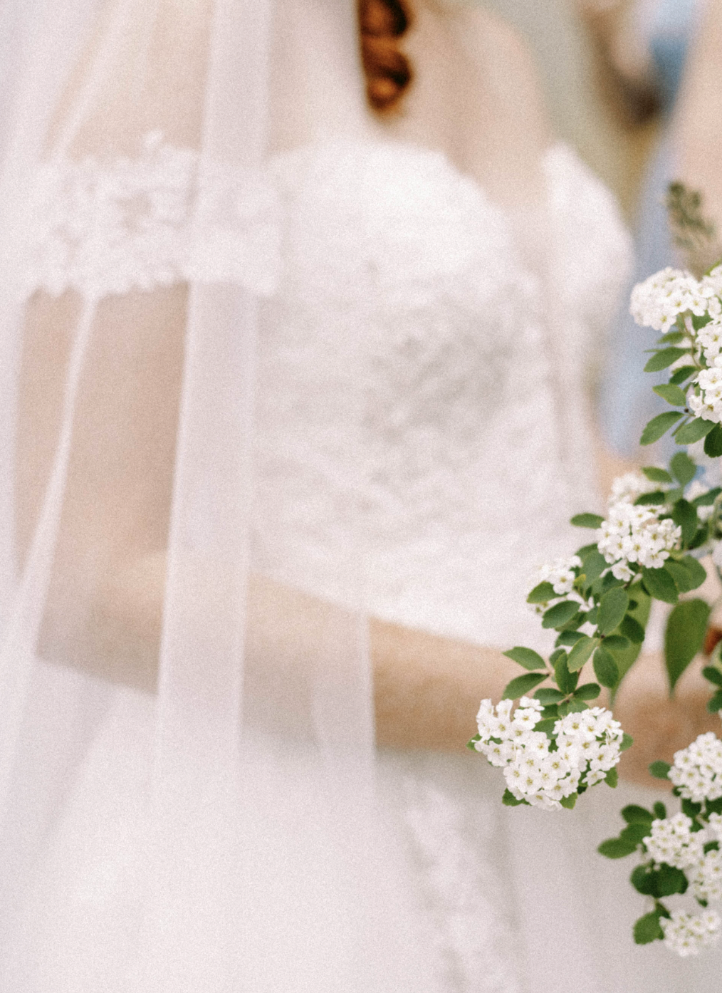 Bride in white lace dress holding bouquet of small white flowers
