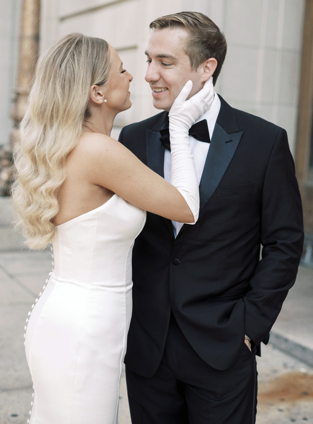 A couple dressed in wedding attire sharing an intimate moment outdoors.