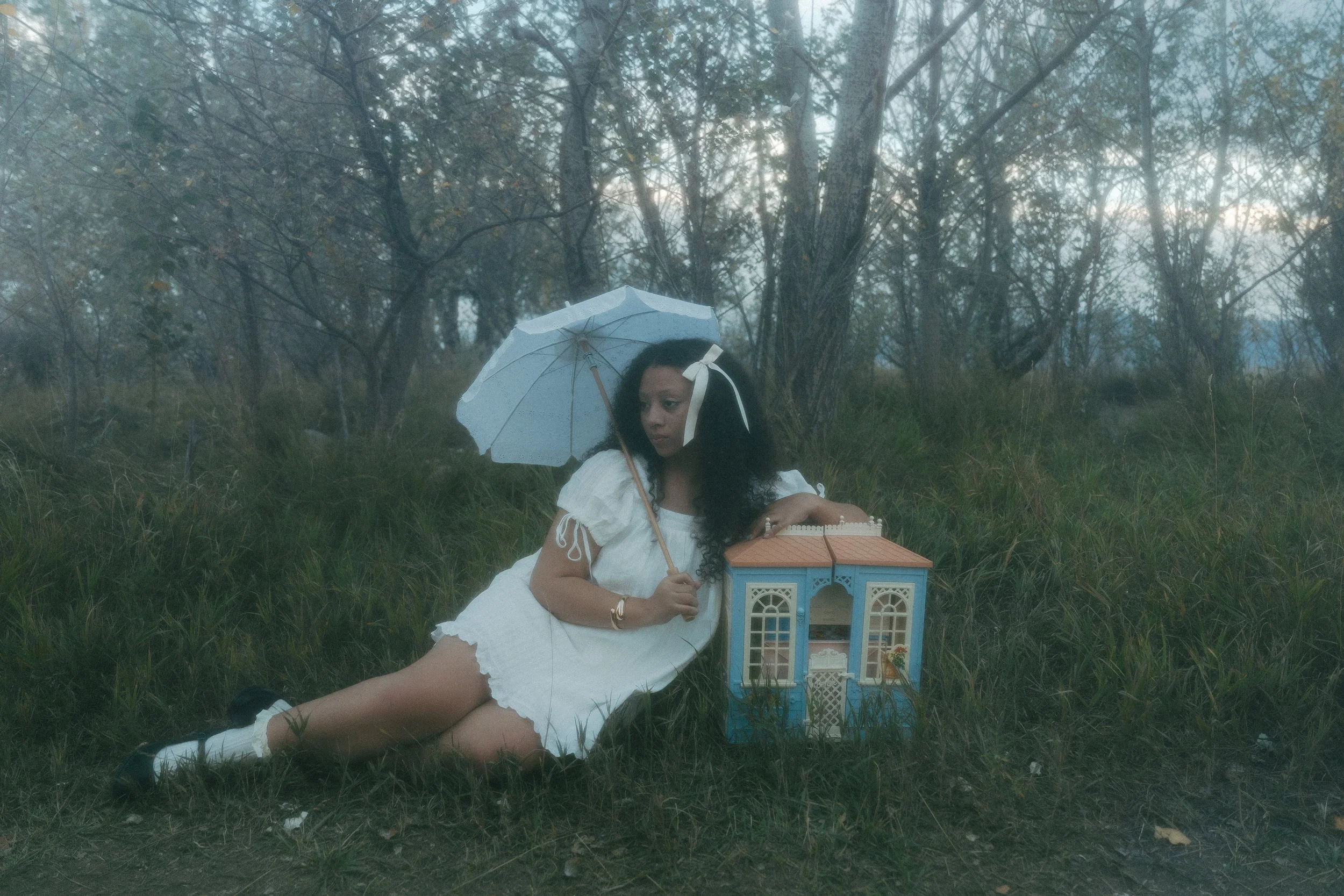 Boulder Colorado senior graduation photoshoot with a girl holding a dollhouse in a dreamy field, whimsical senior portraits, creative graduation photography