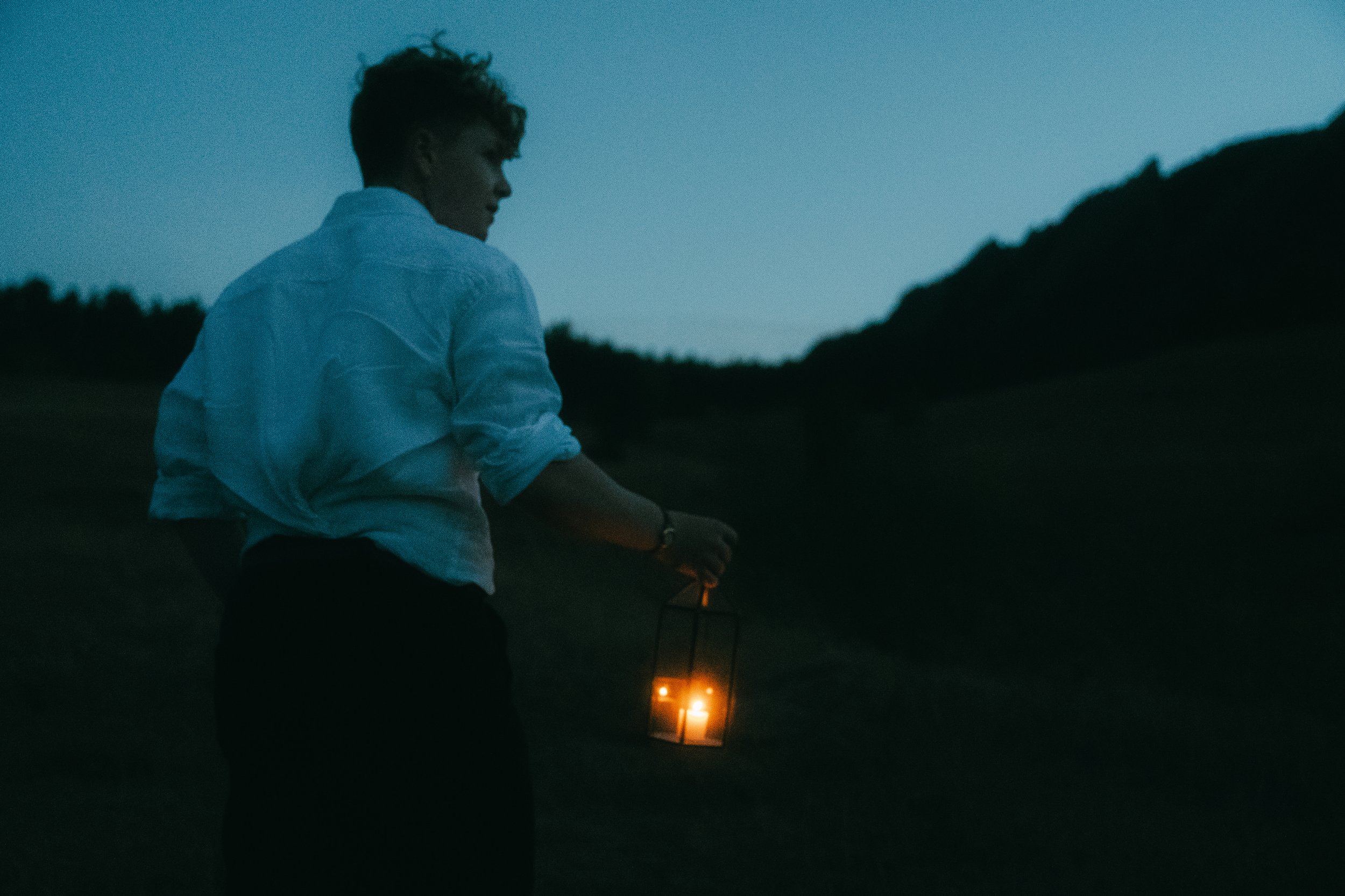 Boulder Colorado senior graduation photoshoot of a boy holding a lantern with the Flatirons mountains at Chautauqua, whimsical outdoor senior portraits, creative graduation photography