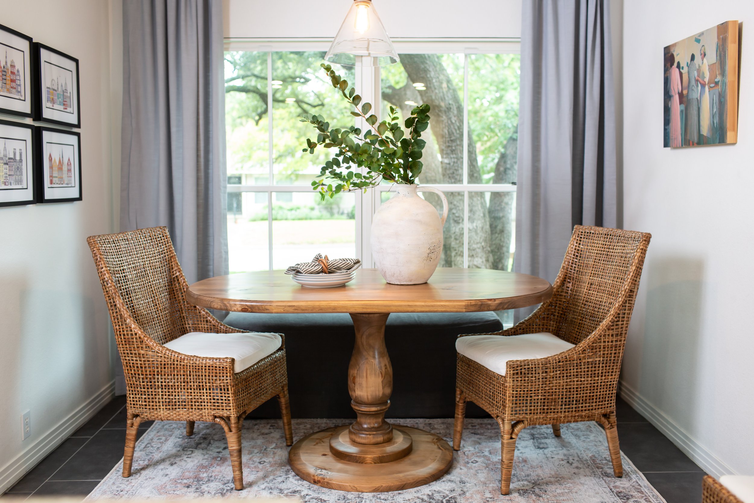 Warm organic breakfast nook featuring woven dining chairs, a round wood table, linen drapery, and natural styling by MASH Habitat Interiors.