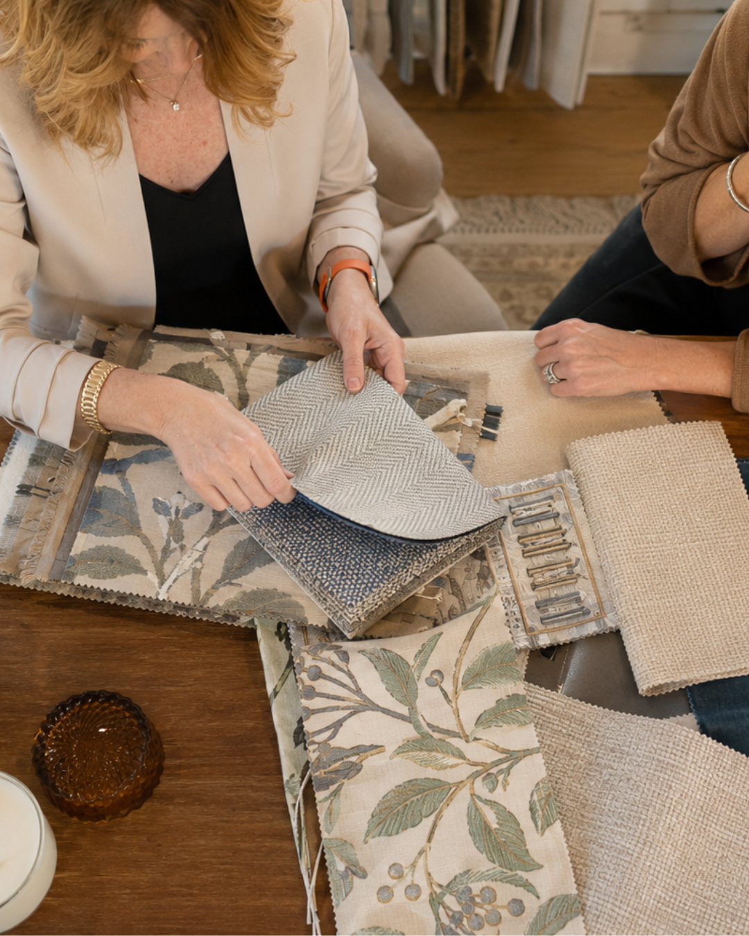 Interior designer reviewing upholstery fabrics and finish selections with a client during a home design consultation.