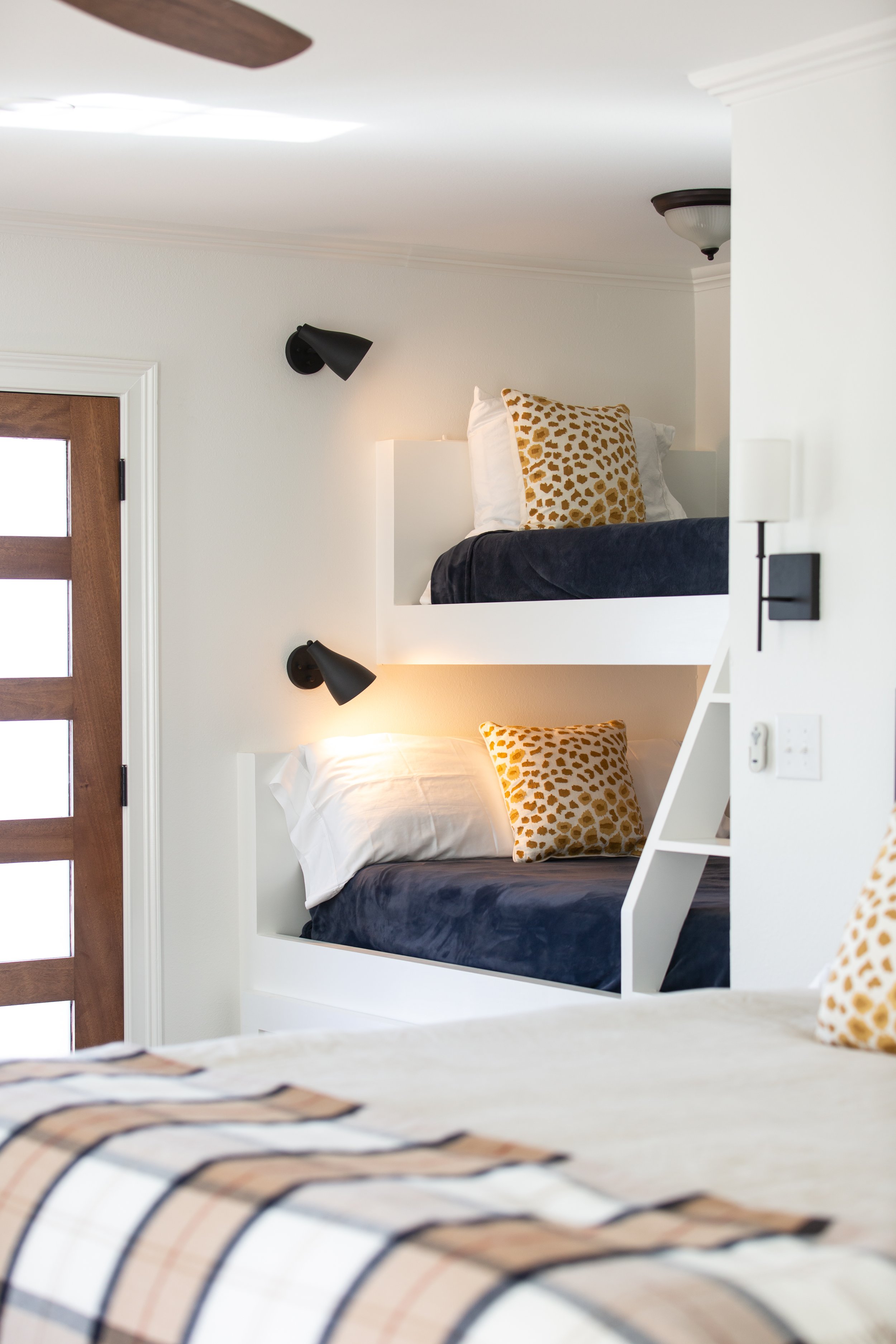 Custom built-in bunk beds with modern lighting and layered textiles designed for a family home by MASH Habitat Interiors.