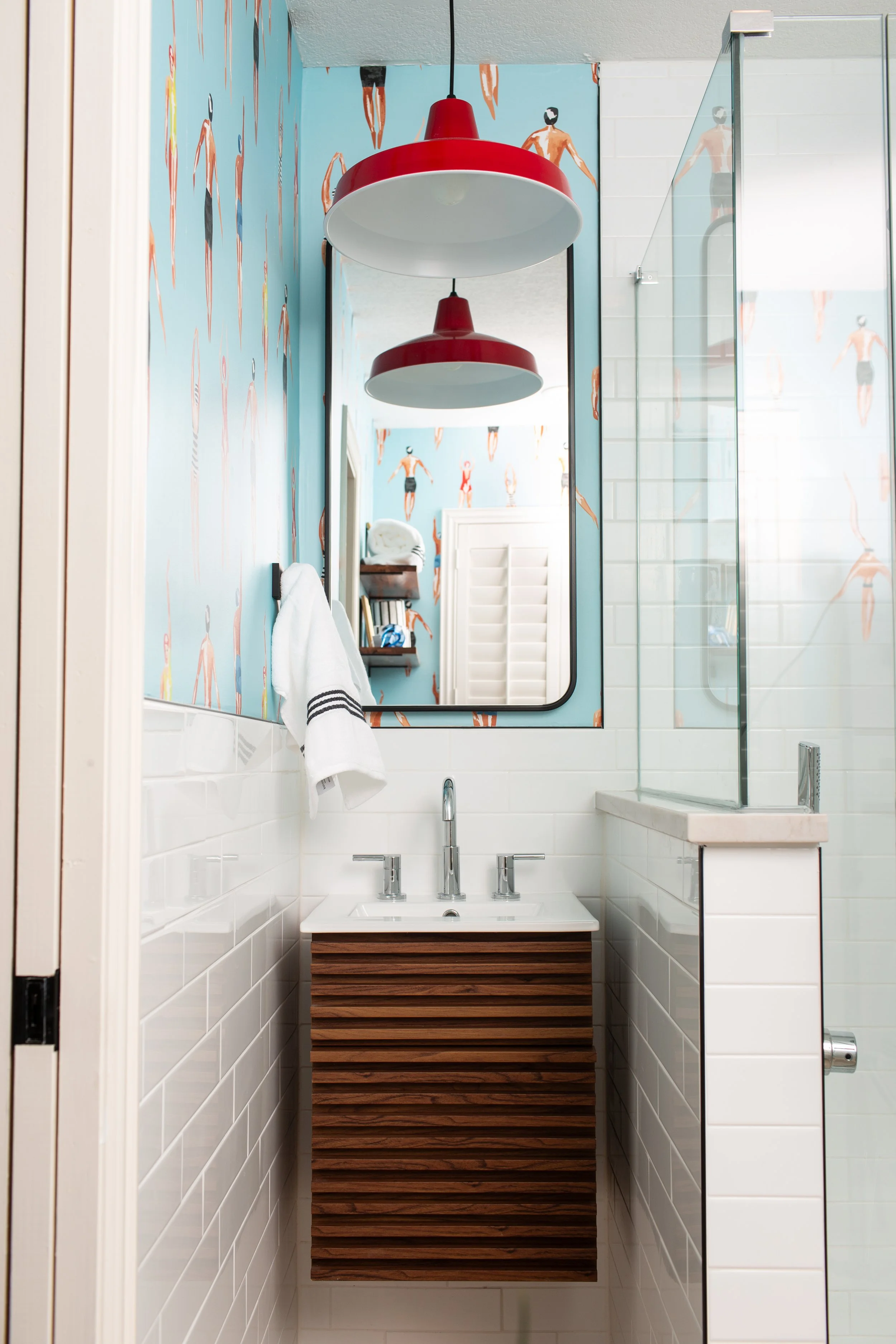 Modern children's bathroom featuring playful wallpaper, custom walnut vanity, and colorful Scandinavian-inspired pendant lighting.