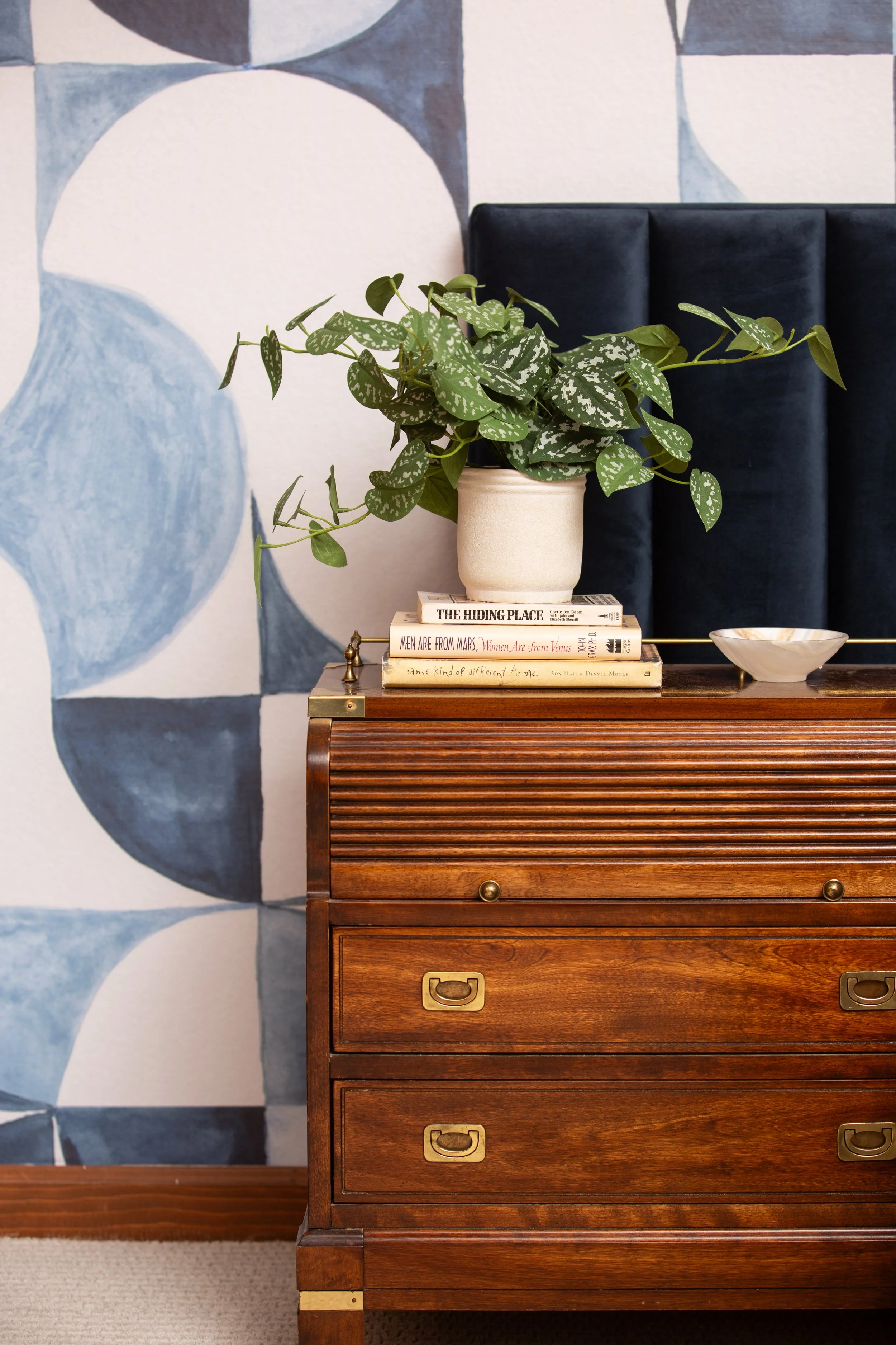 Bedroom featuring a custom geometric mural, vintage wood dresser, upholstered headboard, and layered organic styling by MASH Habitat Interiors.
