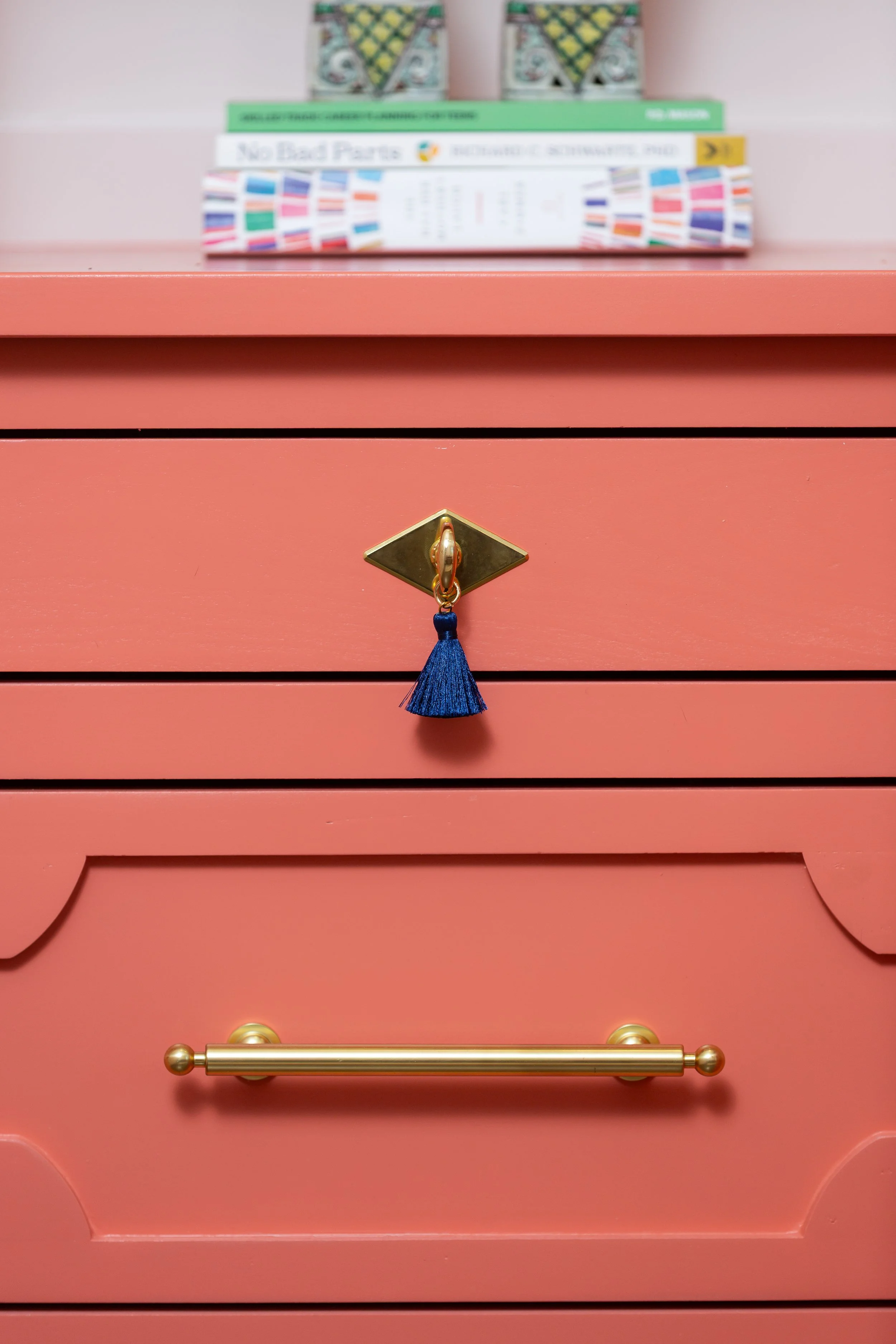 Custom built-in cabinetry detail with coral finish and brass hardware, representing the thoughtful planning and connected decisions behind a successful home remodel.