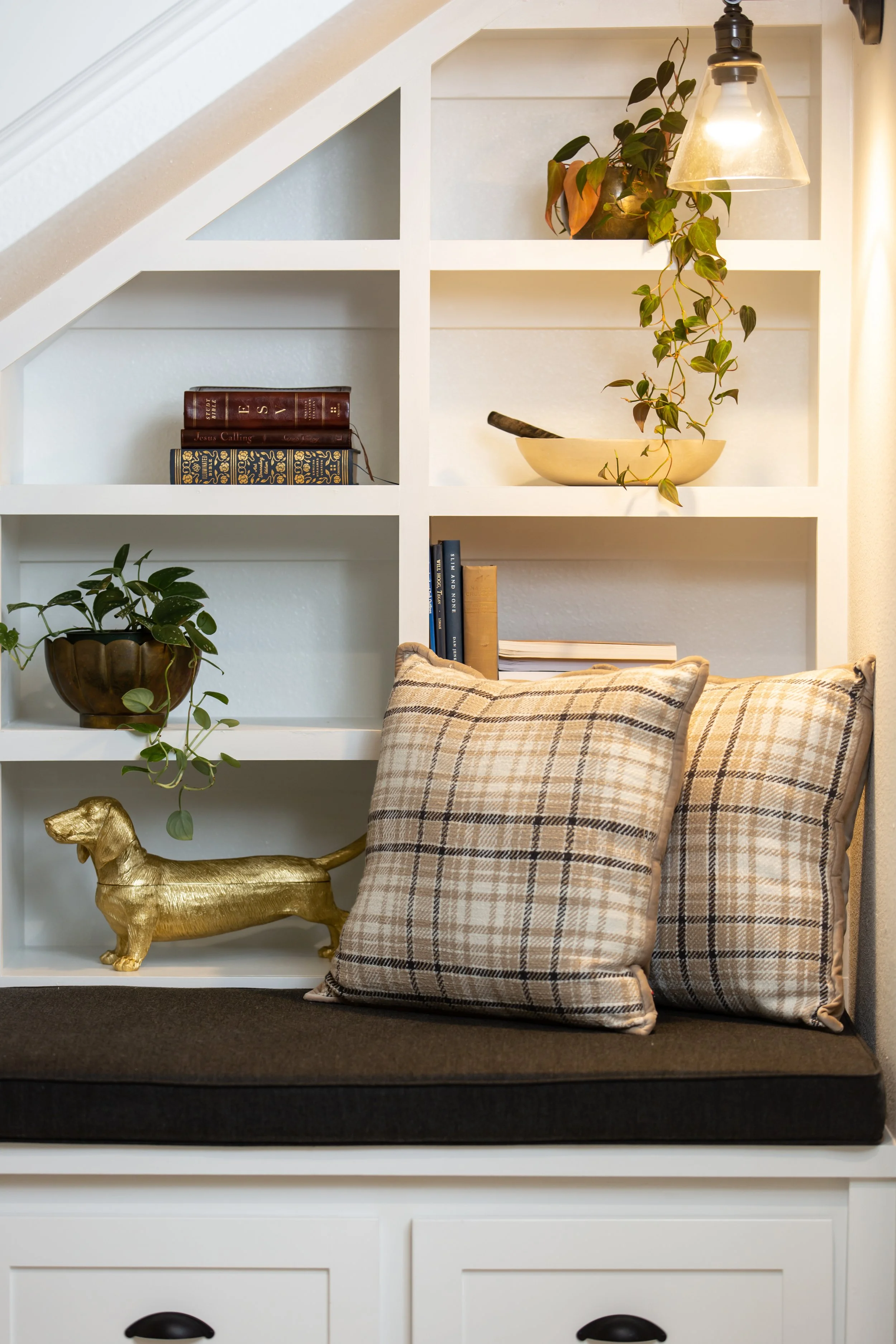 Custom built-in shelving styled with plants, books, lighting, and layered accessories for a warm, collected interior.