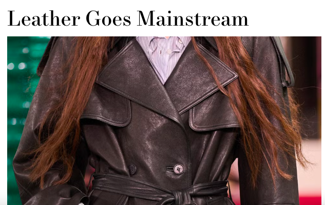 Close-up of a woman wearing a black leather trench coat and a white button-up shirt, with the text 'Leather Goes Mainstream' at the top.