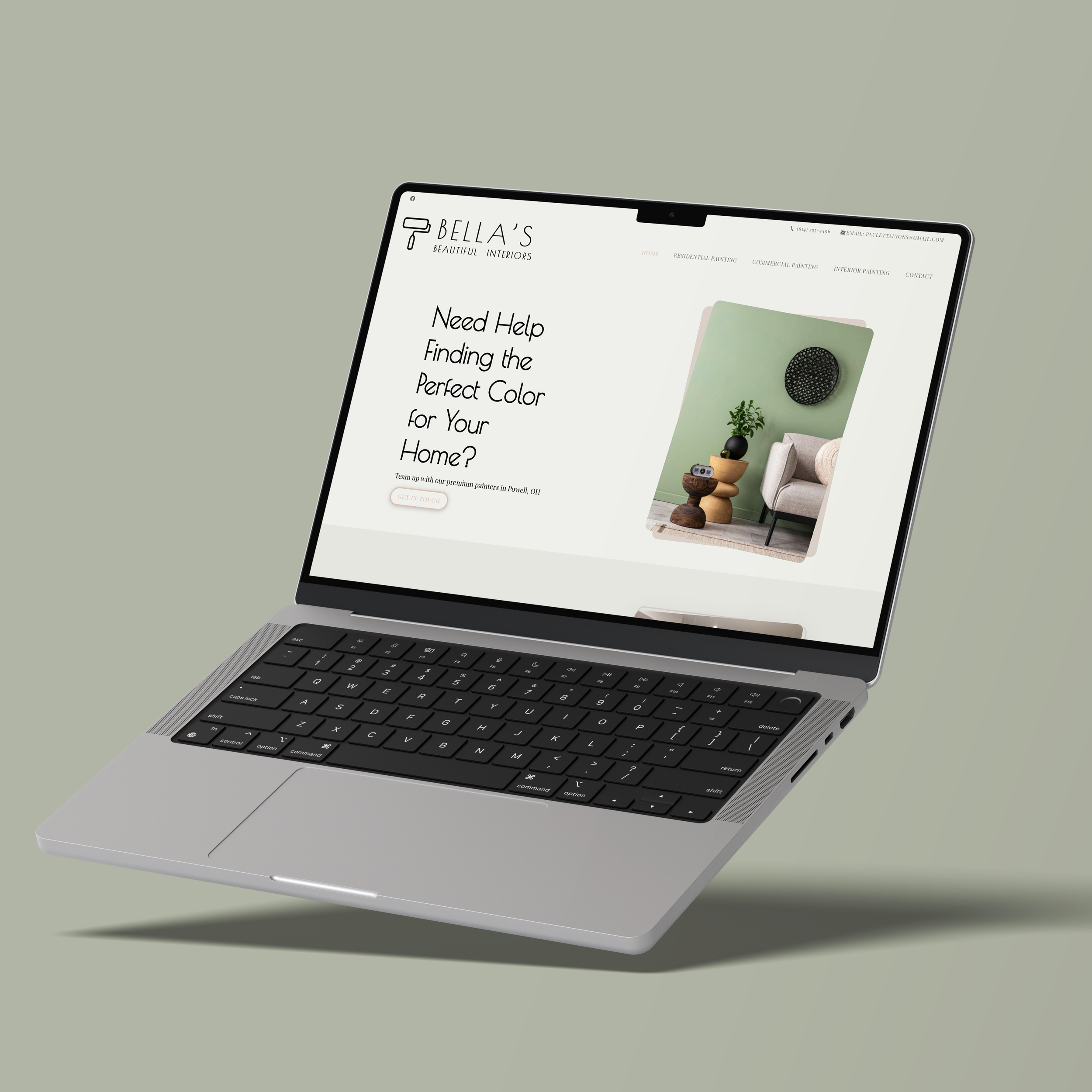 Laptop displaying a website for Bella's Beautiful Interiors, featuring interior painting services and a photo of a modern room with green walls, a beige armchair, and a small round wooden table.