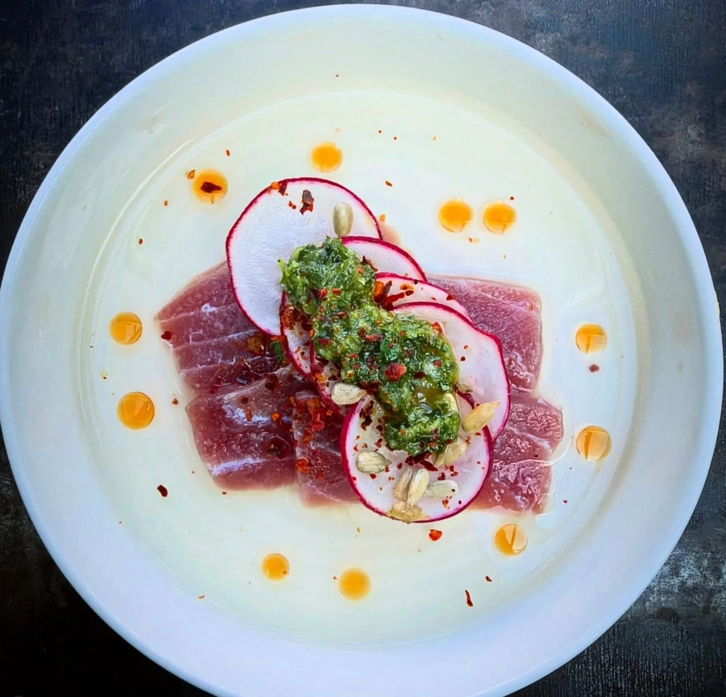 The sun is shining, and we're in a crudo state of mind. Bluefin tuna crudo, smoked bluefin dashi, herb stem salsa verde, chili oil, radish at Viale in Cambridge.⁠
⁠
#crudo #bostonchefs #wulfsfish #newfisholdschool