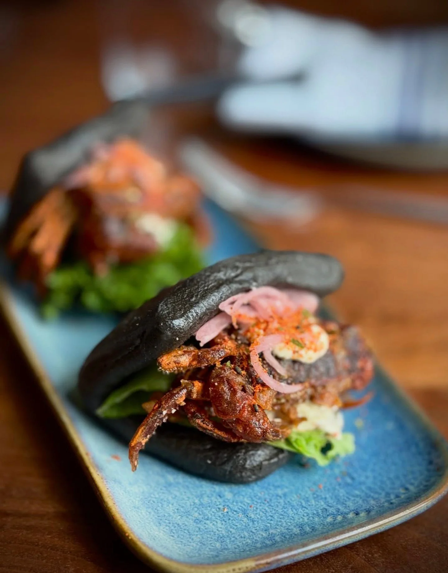 🦀 Squid Ink Soft Shell Green Crab Bao 🦀 at PAGU in Cambridge.⁠
Ramp kimchi alioli, pickled red onion, togarashi 🌶️⁠
⁠
Soft Shell green crabs are showing up on plates. Get them while you can! The season will be short.⁠
⁠
Chefs &mdash; there's still