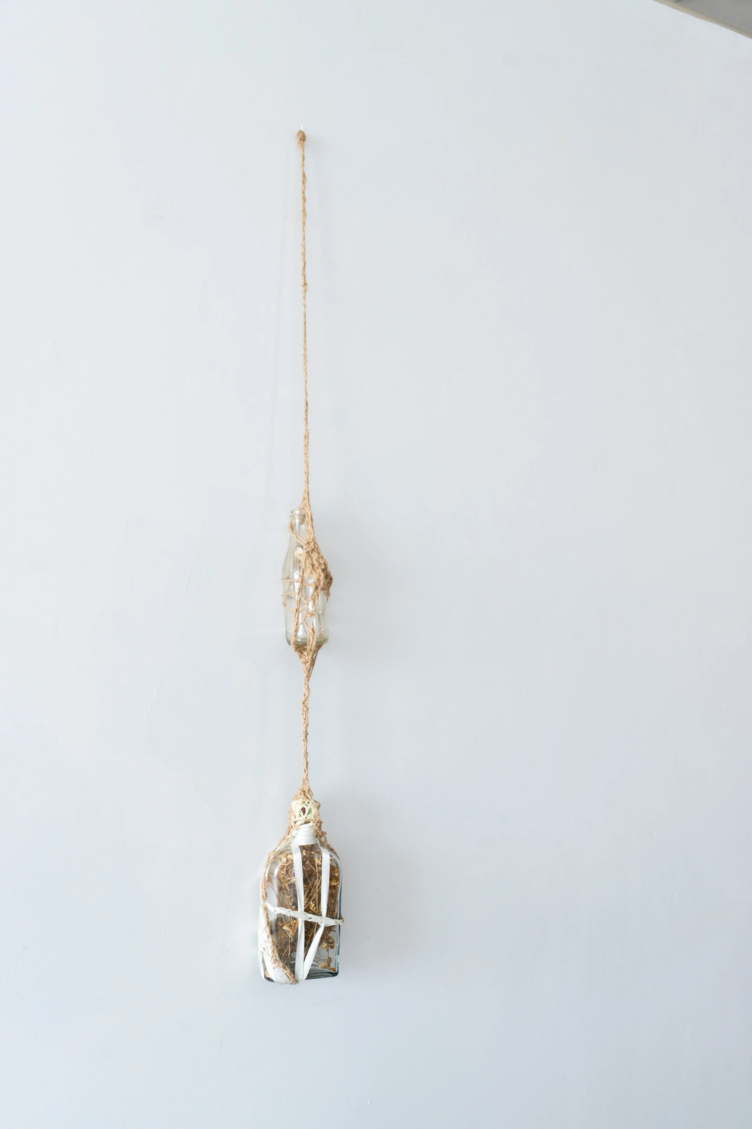 'Daisy Chain'
Antique glass bottles containing dried daisies and chamomile suspended by twine, cotton, and ribbon.