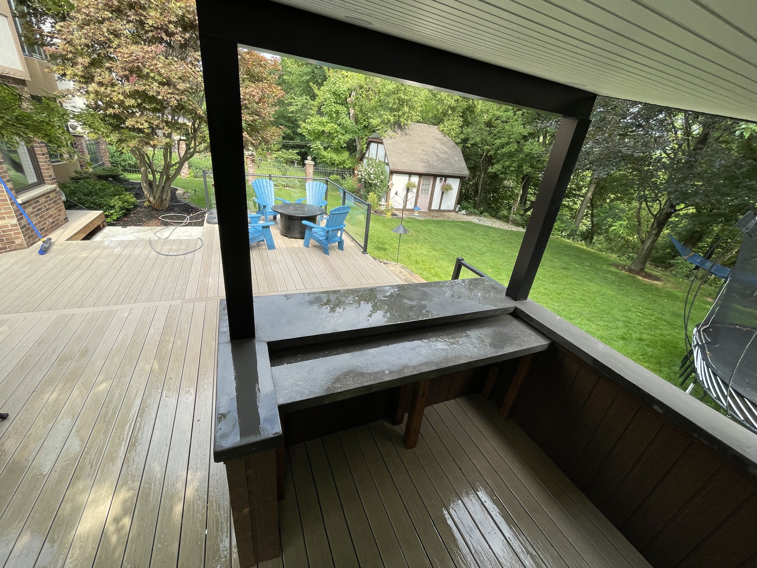 Covered bar with electrical for bar fridge, TV hook-up and stained concrete bar.