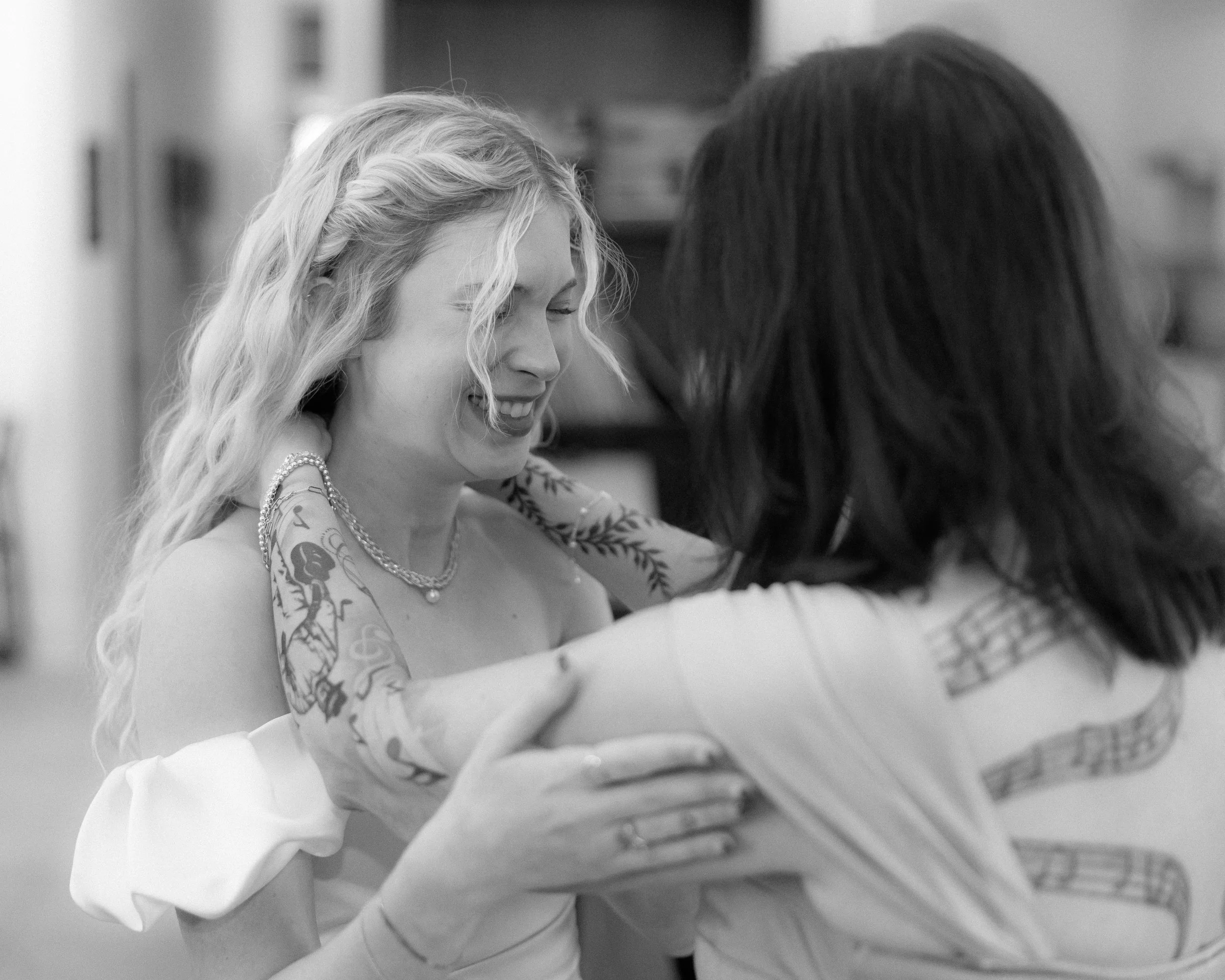 Two women hugging and smiling in a joyful moment, black and white photo.