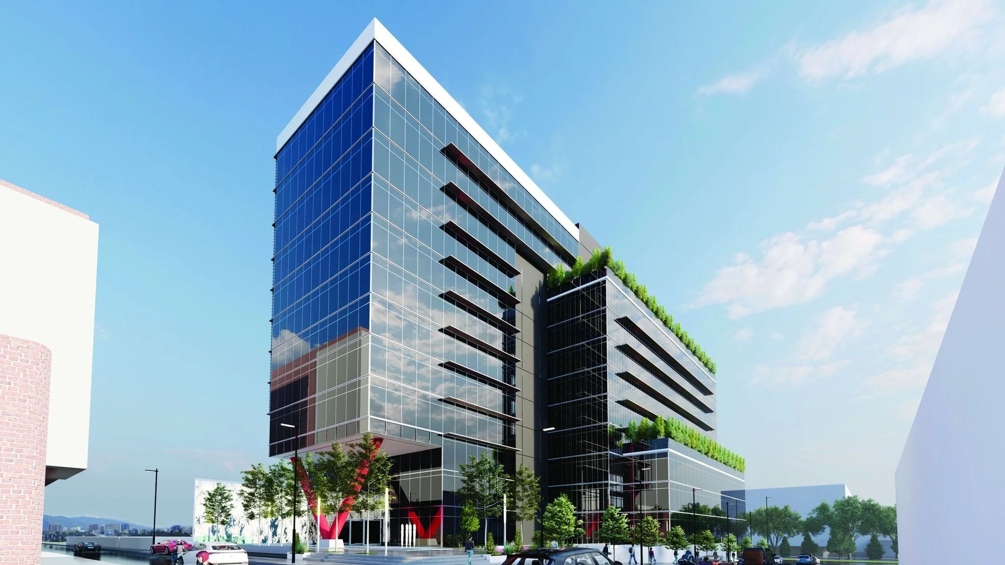 Edificio moderno de oficinas con fachada de vidrio, áreas verdes y automóviles estacionados en la calle.