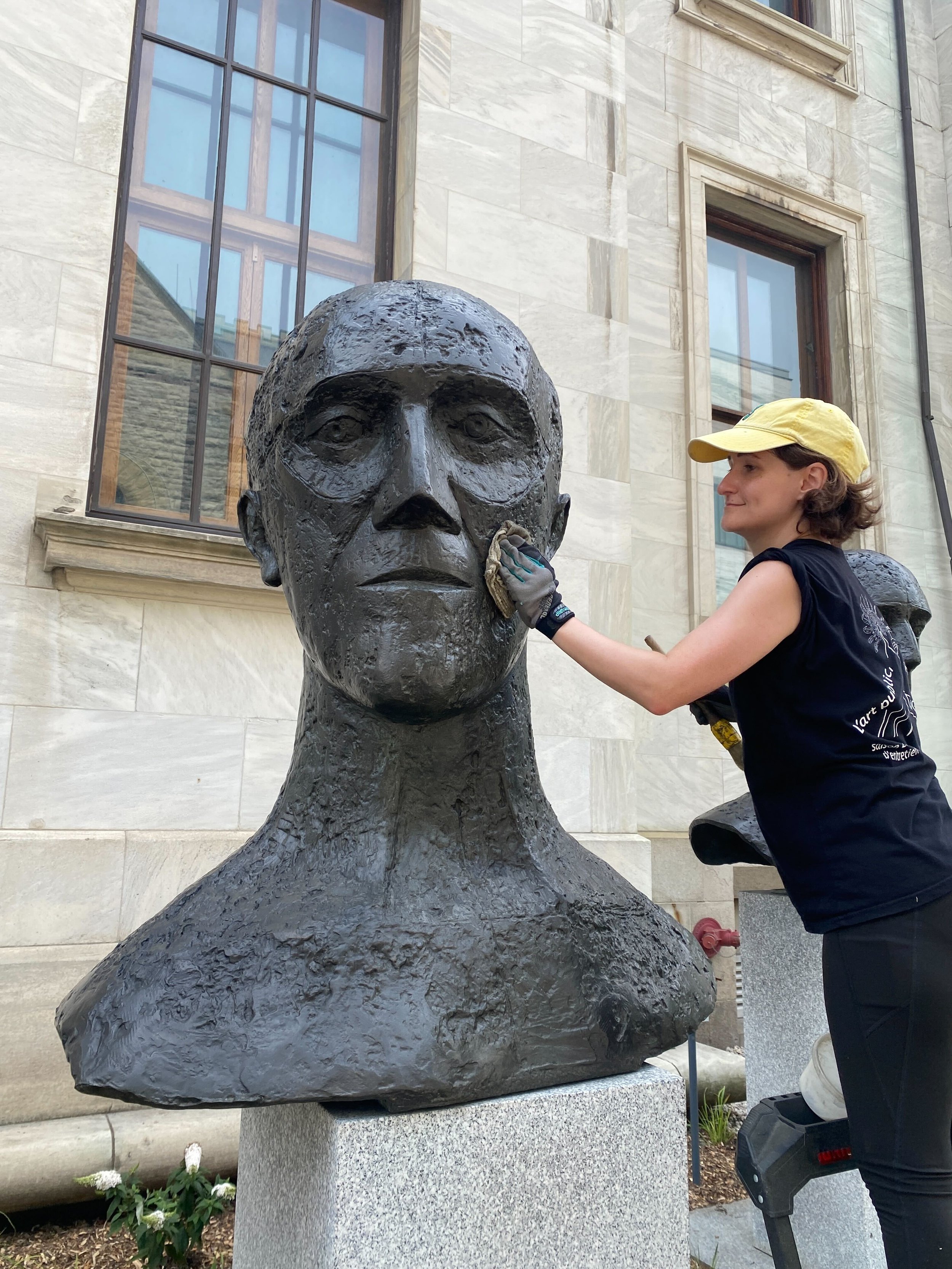 Using a rag to buff wax on one of two bronze busts
—
"In memoriam I" and "In memoriam II" (1981) by Elisabeth Frink