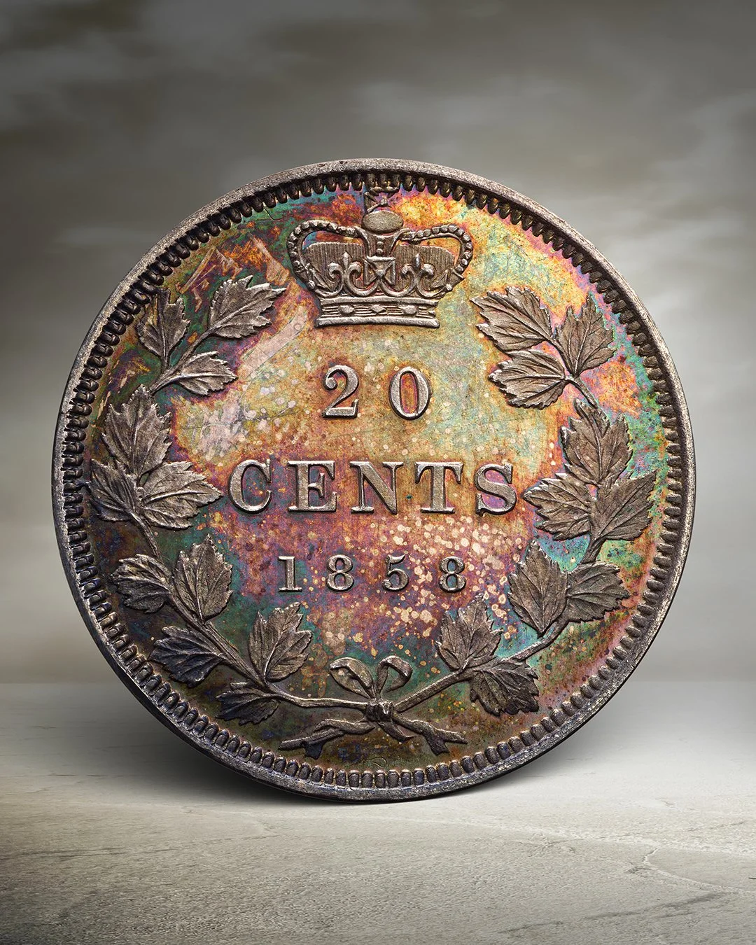 Close-up of an old 20 cents coin from 1858 with a crown at the top and a wreath around the edges, showing signs of tarnish and colorful iridescence.