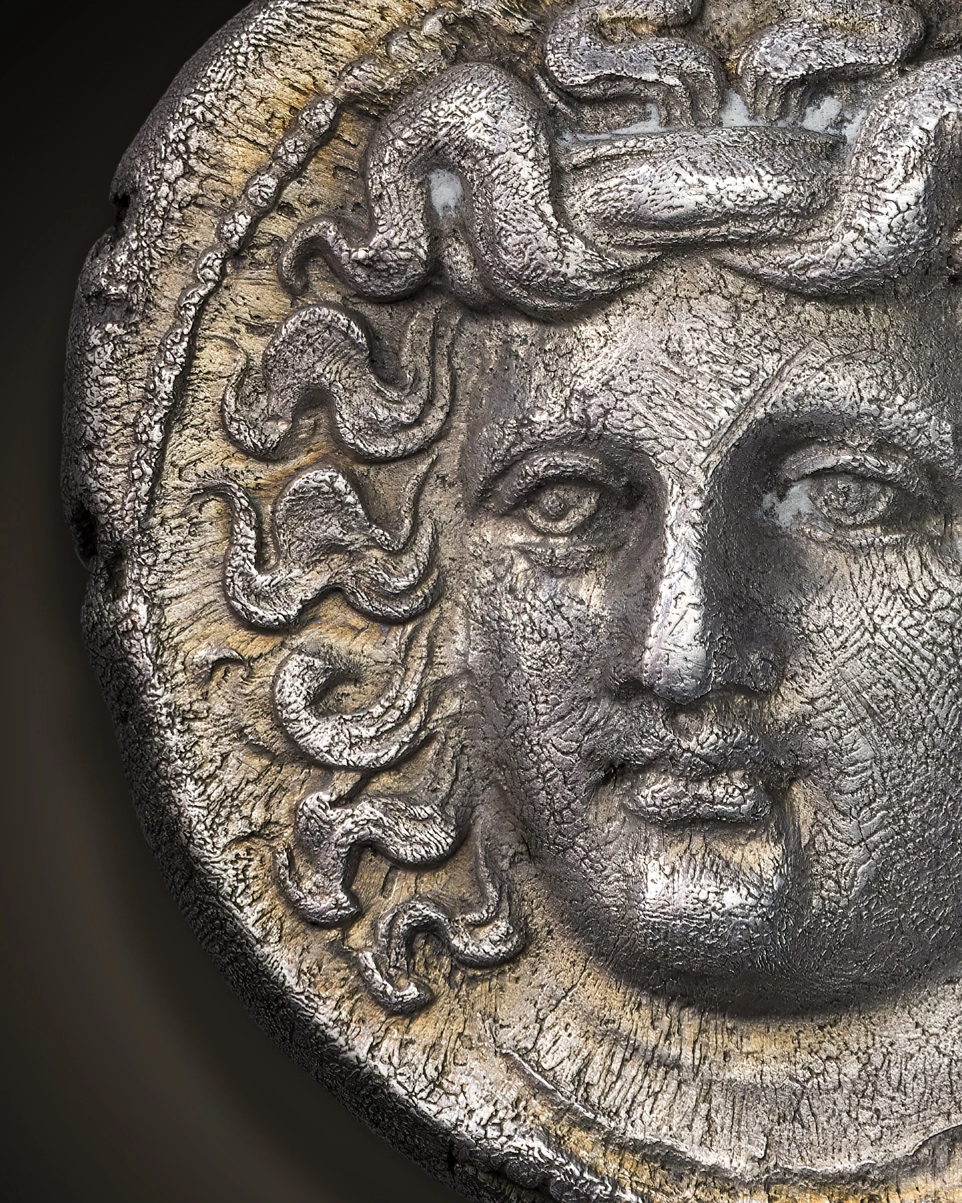 Close-up of a textured, weathered ancient coin of Larissa with curly hair.