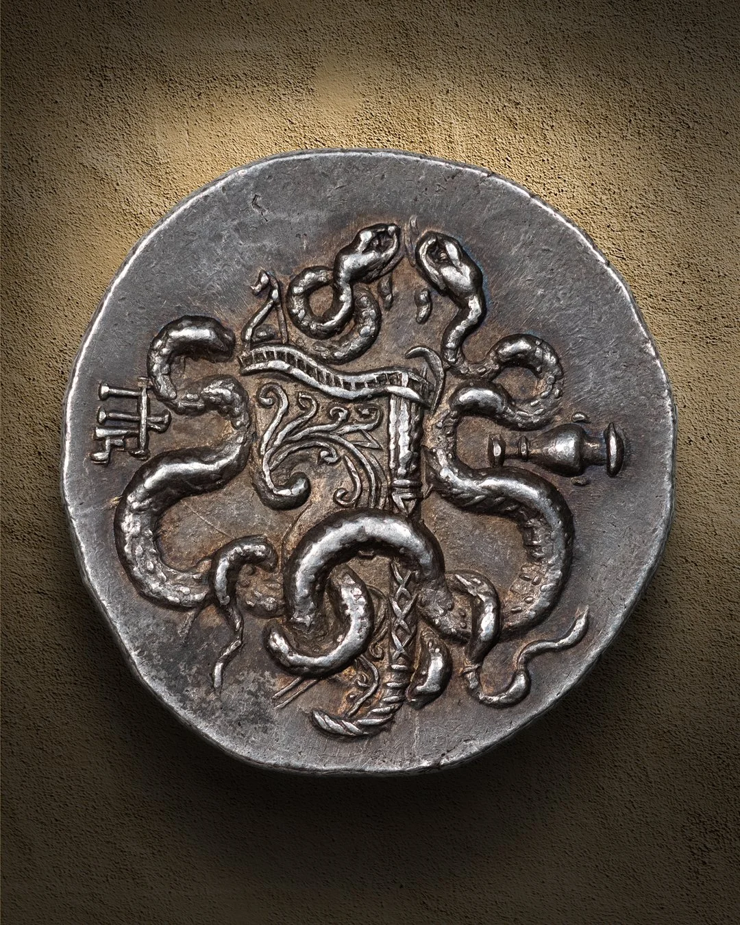 Ancient silver coin with a design featuring an octopus with multiple tentacles, and various symbols around its body.