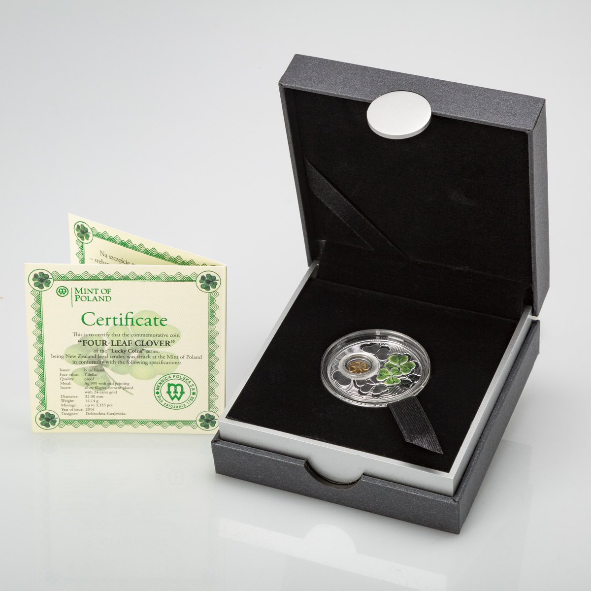 A black presentation box containing a commemorative coin with a four-leaf clover design, a certificate of authenticity from Poland, and a protective display case for the coin.
