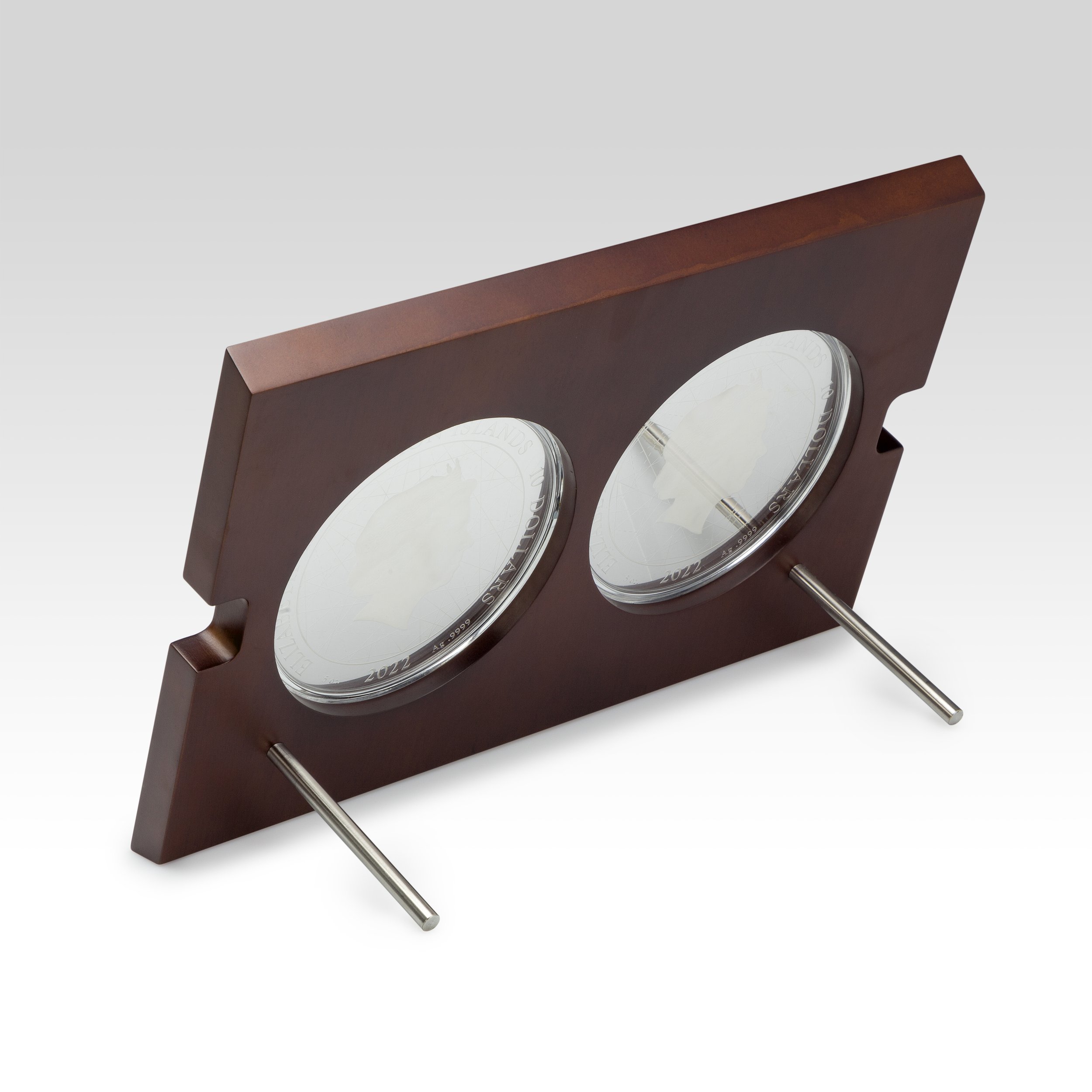 A wooden plaque with two silver medals and metal stems for mounting.