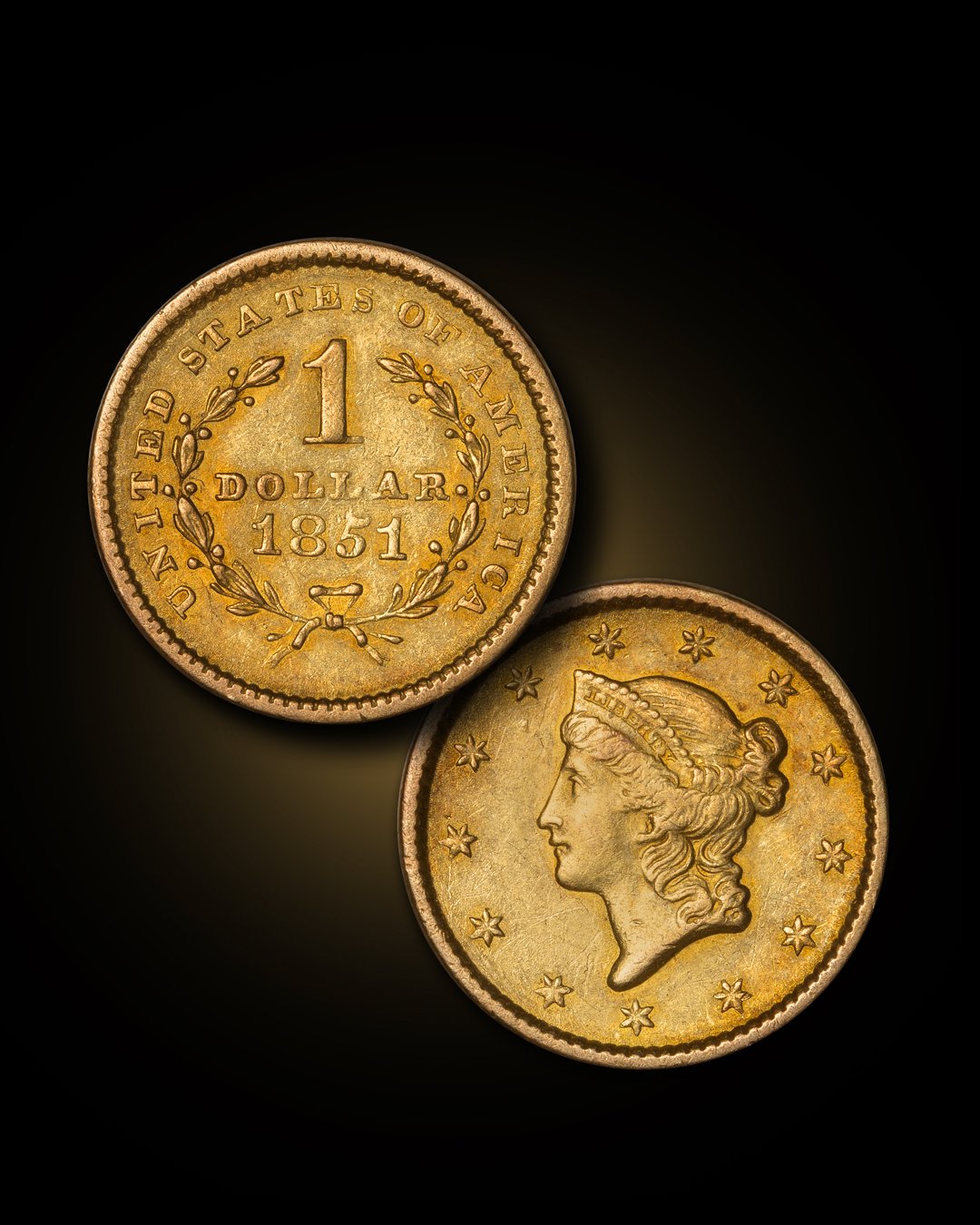 Close-up of two US one-dollar coins from 1851, showing the obverse with a woman's profile and the reverse with the denomination, year, and a wreath, against a black background.