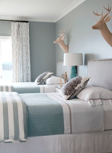  This room is pretty monochromatic with the icey blue walls and turquoise bedding. &nbsp;The upholstered headboards and drapes really soften up the room and the faux deer heads provide a fun twist to a more traditional space.  Image:&nbsp; Bear Hill 