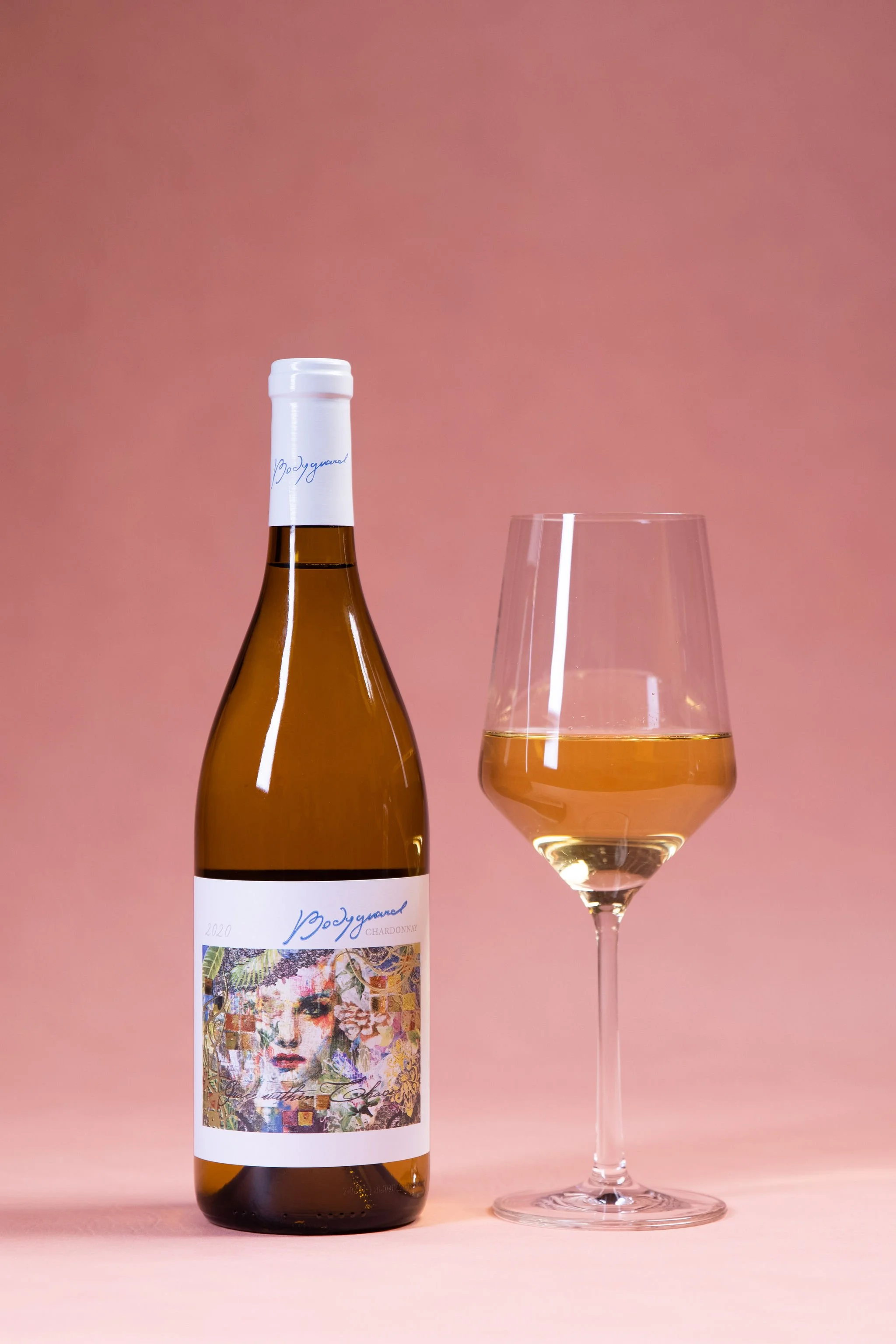Bottle of white wine with glass on pink background
