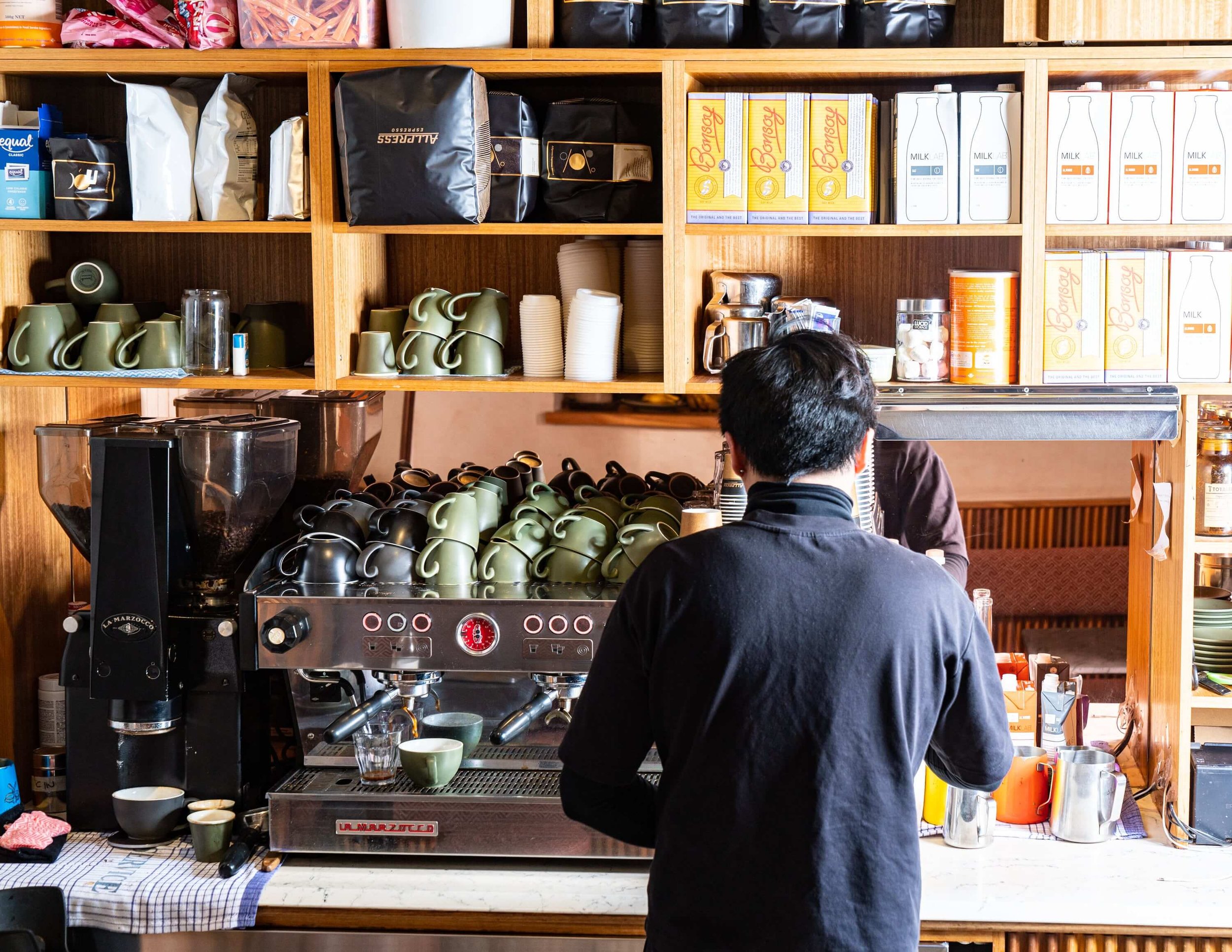  Barista making fresh espresso in a fully stocked cafe 