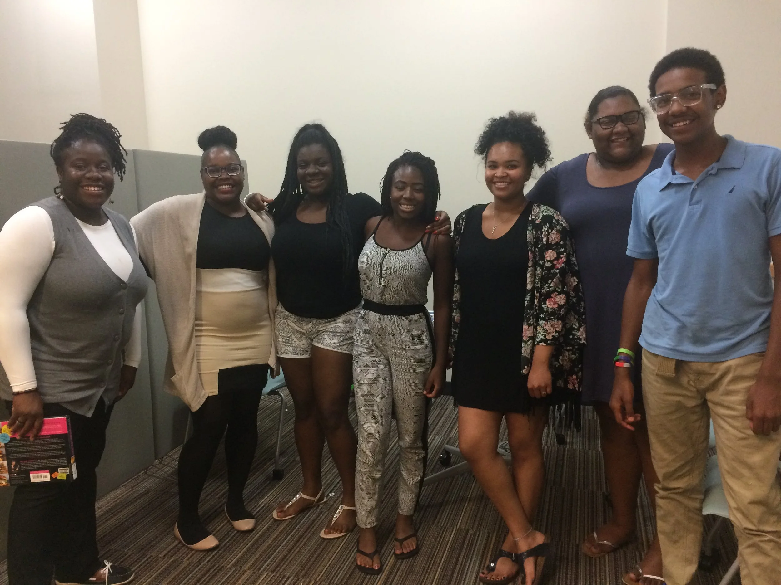 A group of women standing shoulder to shoulder smiling