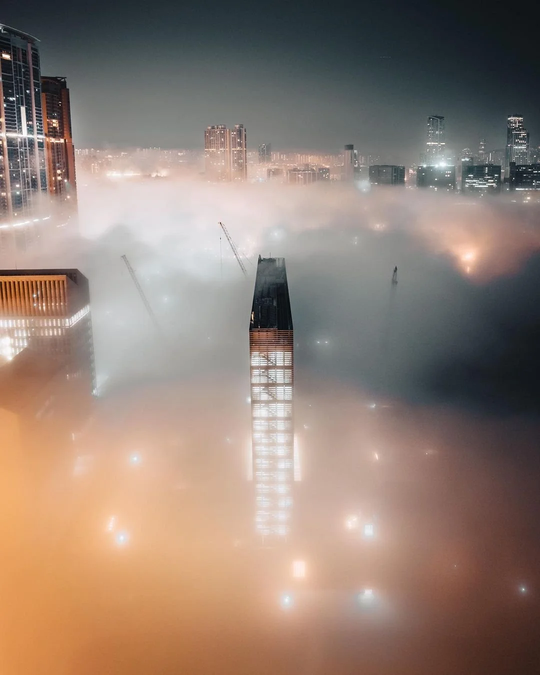 Aerial image of the M+ Art Museum surrounded by clouds at night
