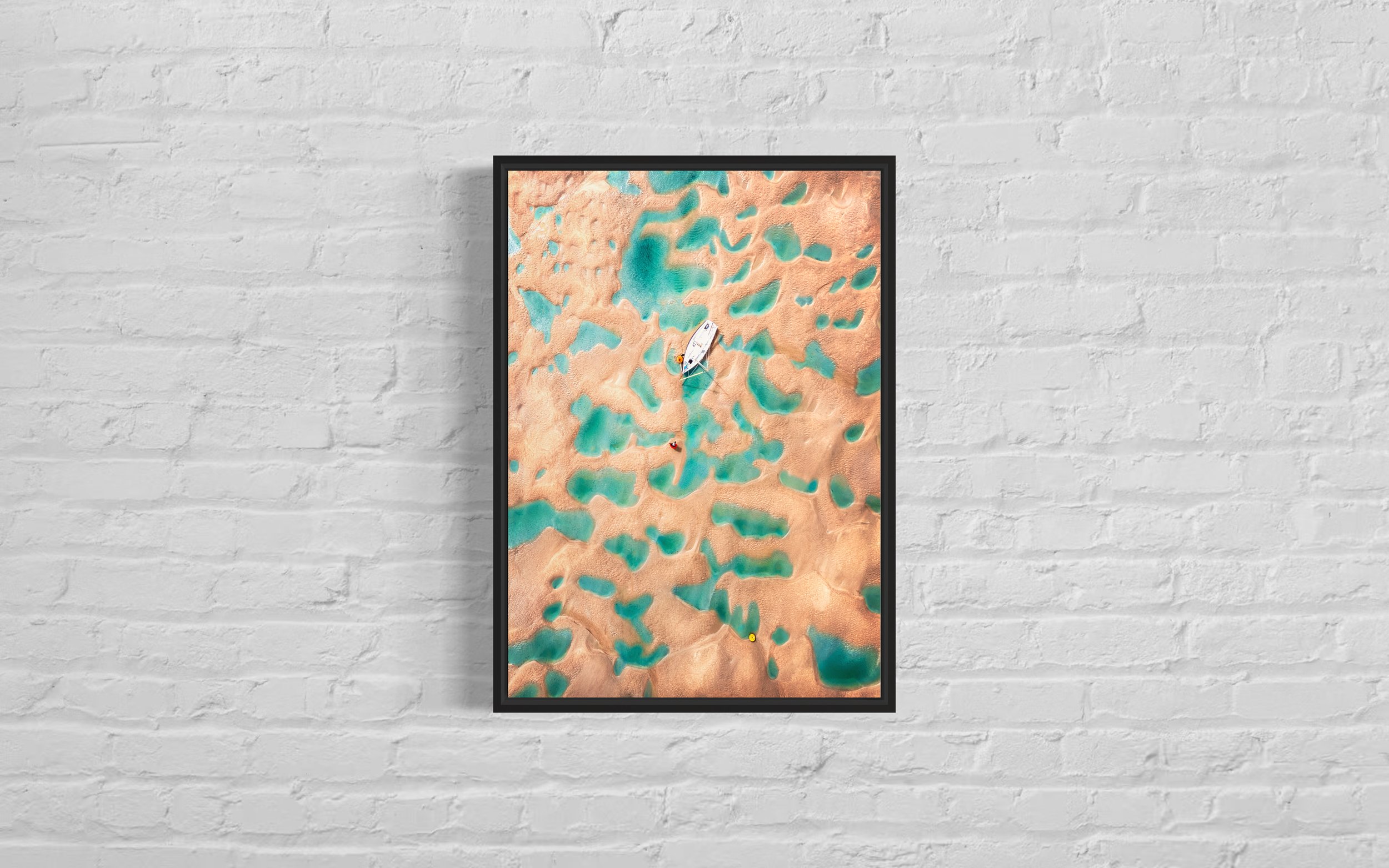 High-quality framed print showing an aerial image of a lone fisherman navigating between the rock pools at the Doom Bar, Cornwall.