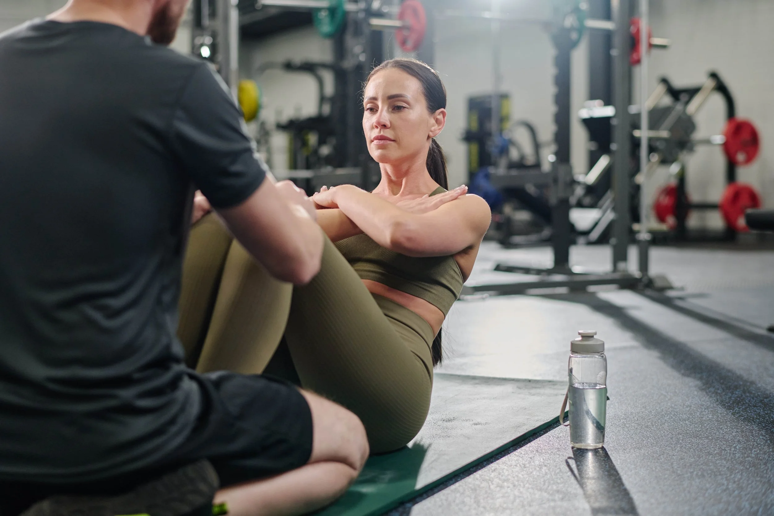 A woman receiving an injury consultation from a trainer or physical therapist at the gym.