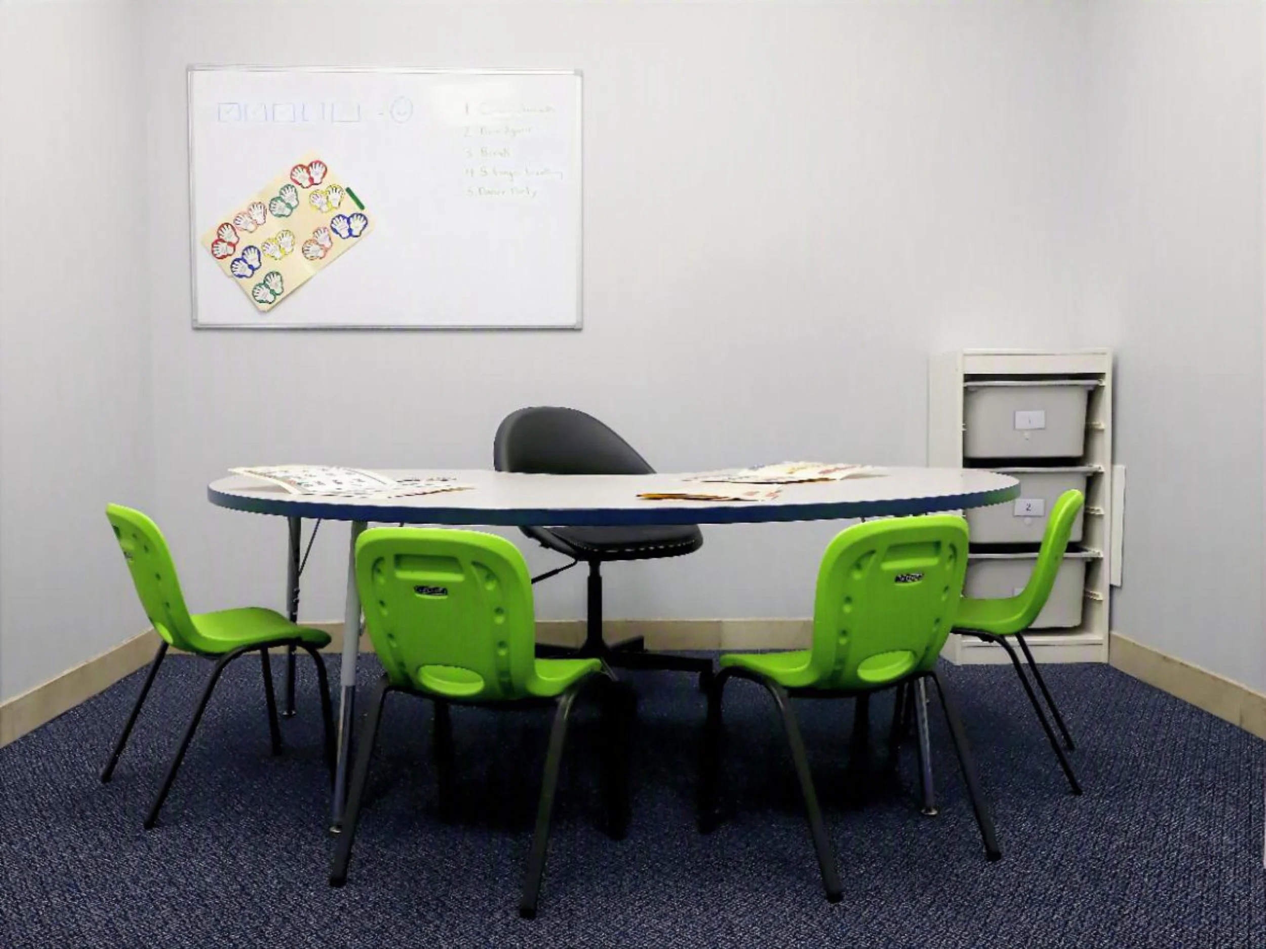 A group therapy room at Ascent Clinical Services with a round table, child-sized chairs, learning materials, and a whiteboard — set up and ready for a small group session