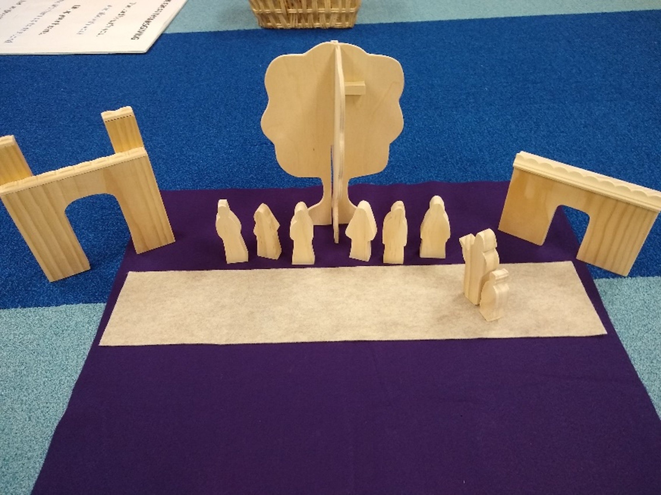 Wooden dominoes and blocks arranged to resemble the biblical scene of the Last Supper, with a purple and gray cloth background.
