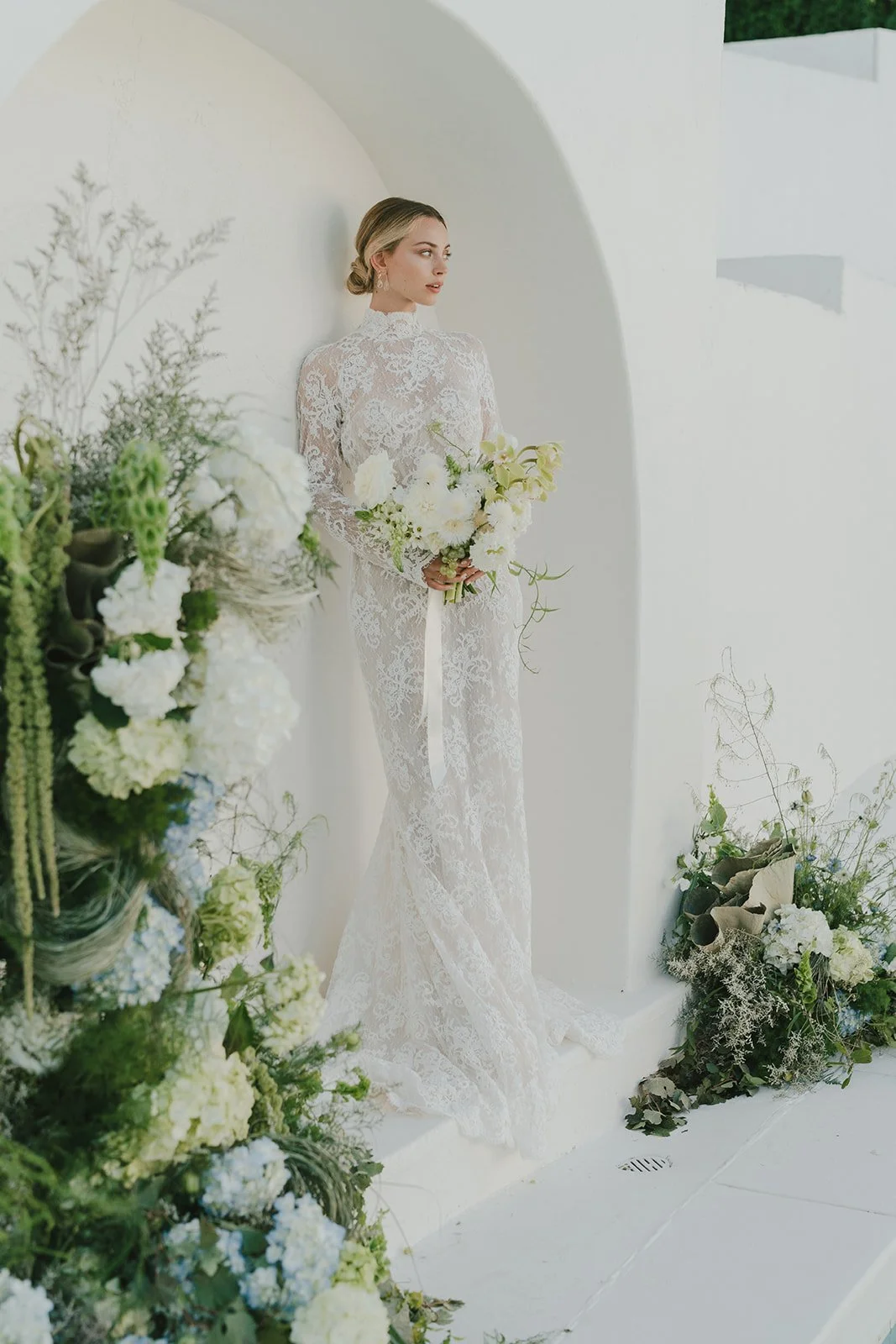 Bride holding bouquet in sculptural white ceremony space.