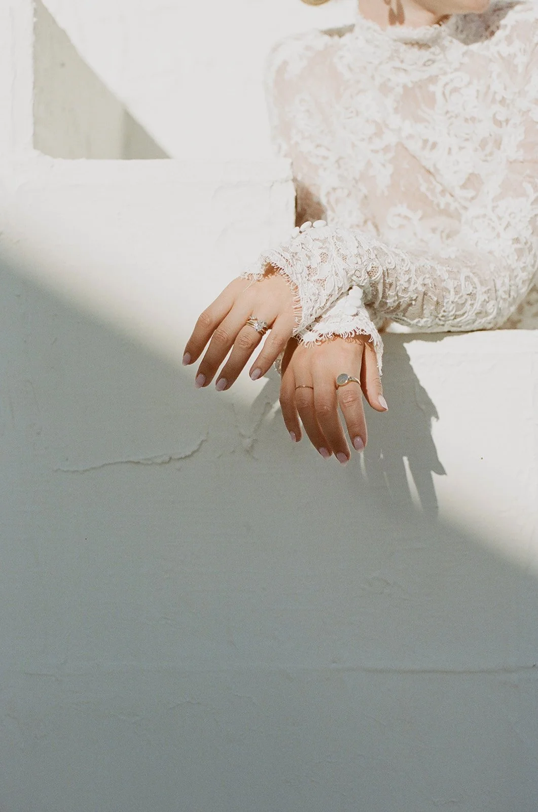 Close-up of bridal hands with delicate lace sleeves.