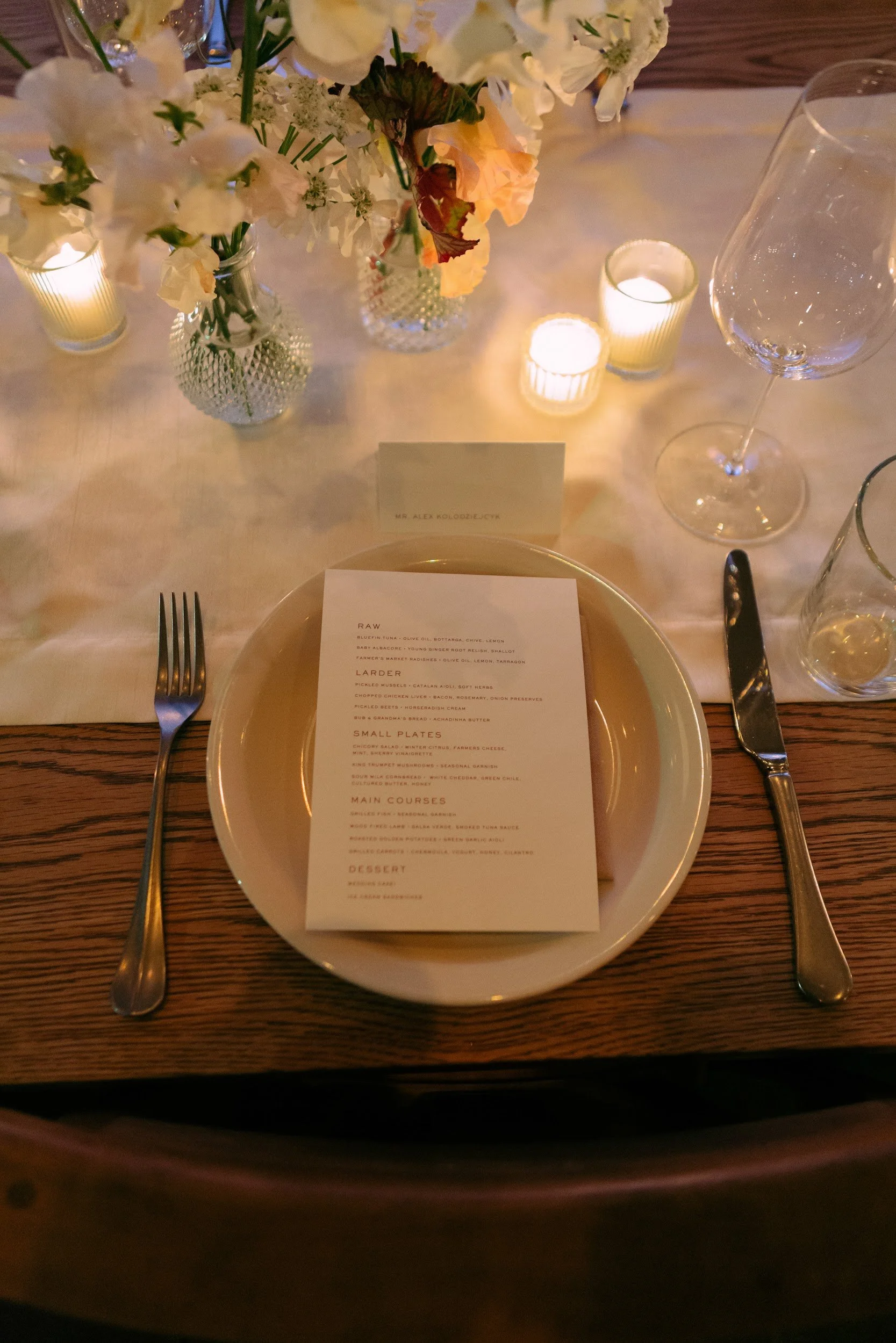 Candlelit wedding tablescape with floral arrangements and printed menu at a Los Angeles restaurant reception.